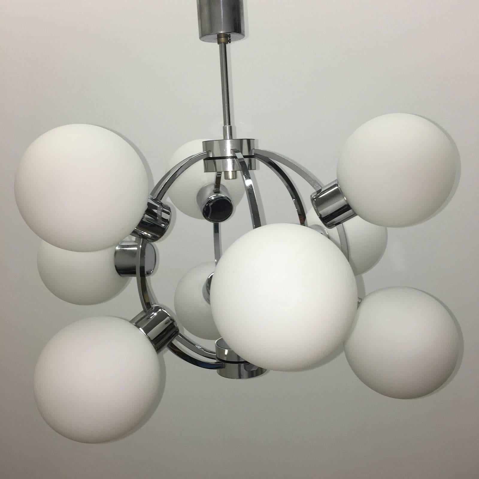 A nine-arm circa 1960s chrome milk glass Sputnik orbit chandelier with interior lights. Each Fixture requires nine European E14 candelabra bulbs, each bulb up to 40 watts.
