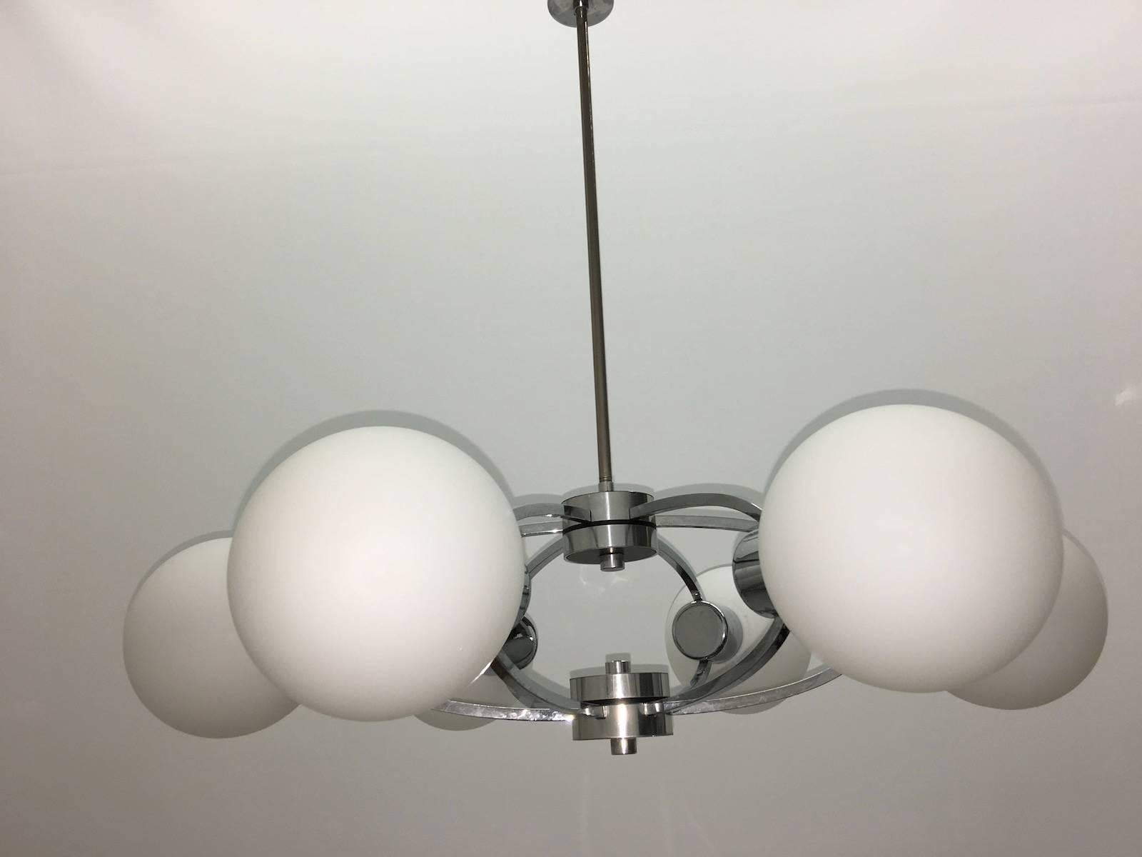 A six-arm chrome milk glass Sputnik chandelier with interior lights, circa 1970s. Each fixture requires six European E14 candelabra bulbs, each bulb up to 40 watts.