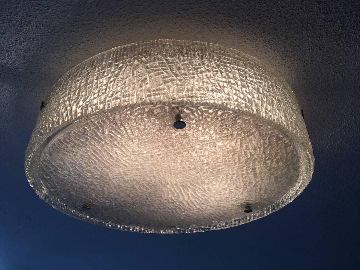 Large Mid-Century circular flush mount light by Kaiser Leuchten, Germany, 1960s. The glass shade comprises two pieces of heavily textured clear glass pinned to a white metal frame with screw-in metal fixings.
This piece requires four E27 Edison