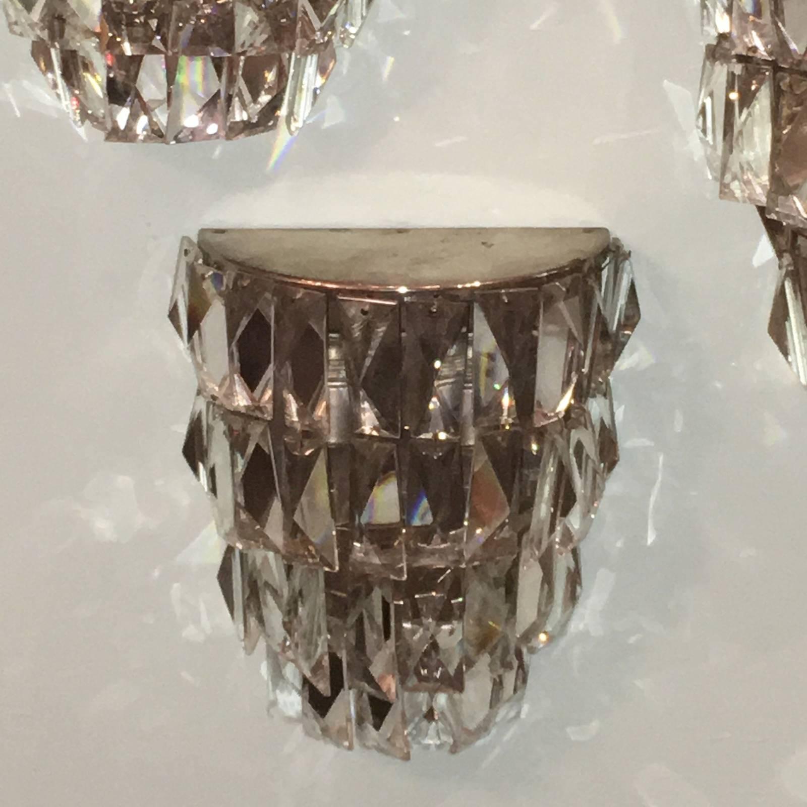 Lot of 4 sconces with 34 individual faceted crystals hanging on a chrome armature. Each fixture requires two European E 14 candelabra bulbs up to 40 watts each.