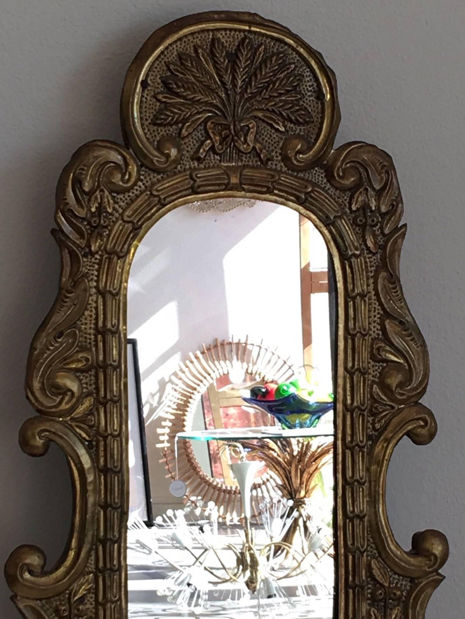 This mirror was designed and constructed during Germany's Baroque era, 18th century. It was originally build to be a standing mirror. Sometime during the 19th century it was converted into a hanging wall mirror. The back foot was removed and a new
