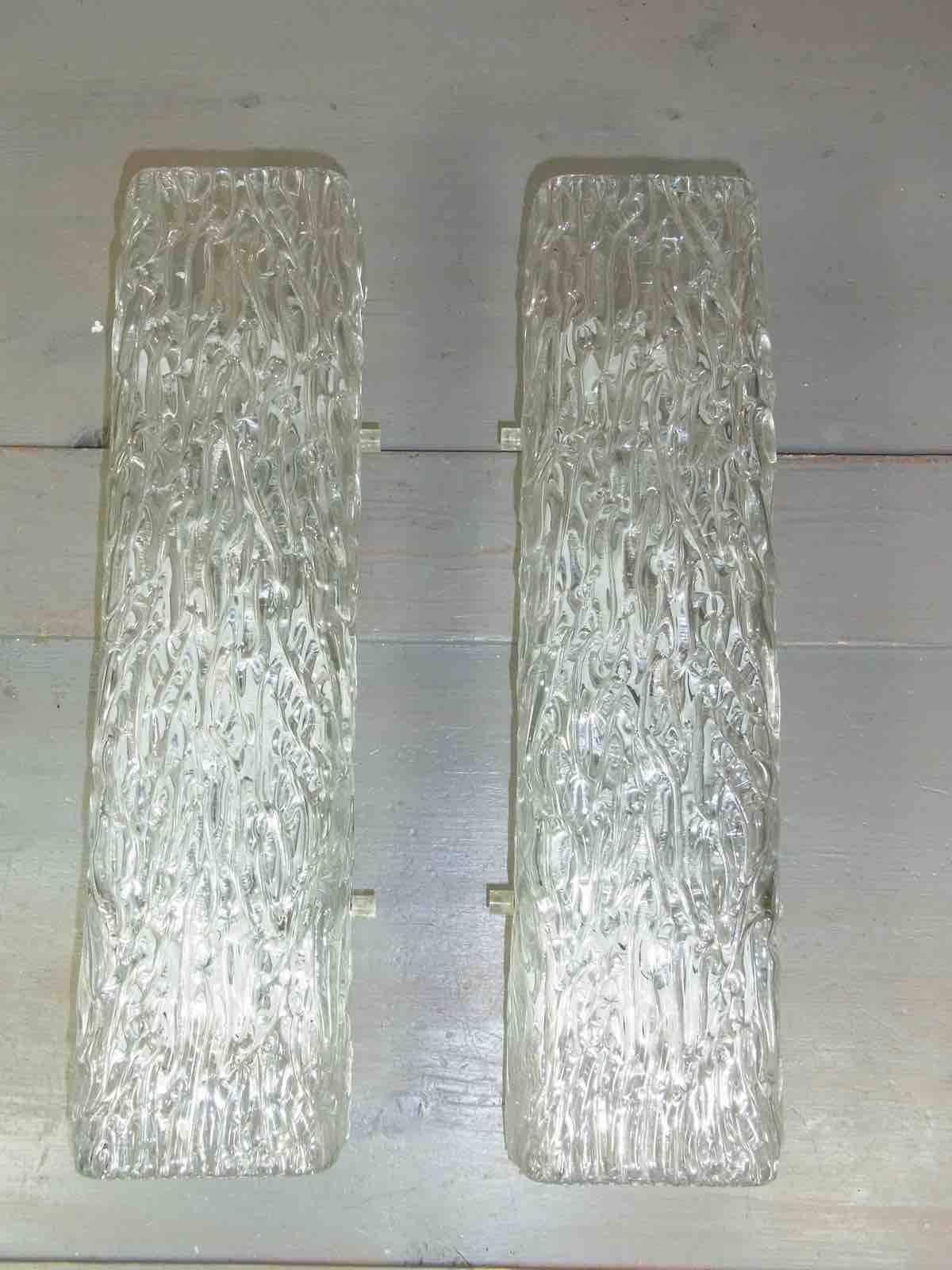 A pair of heavily textured ice glass vanity sconces. Thick ice glass on a backplate. Each fixture requires three European E14 candelabra bulbs, each bulb up to 40 watts.