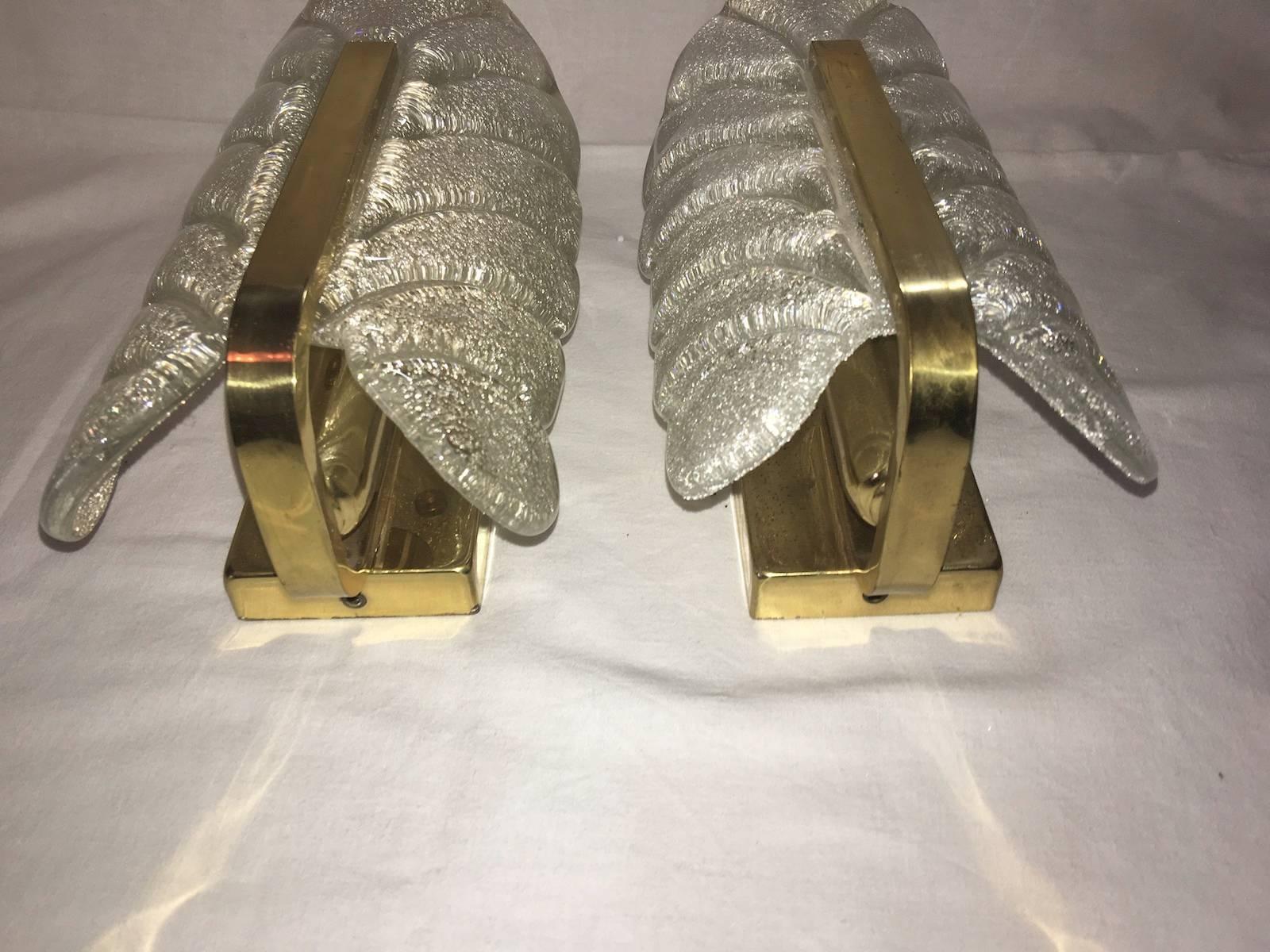Very glamorous wall sconces designed in the style of Carl Fagerlund for Orrefors glass, manufactured in Mid-Century, circa 1960-1969. Each sconce features a polished brass frame with one glass leave which have a matte frosted relief on the inside