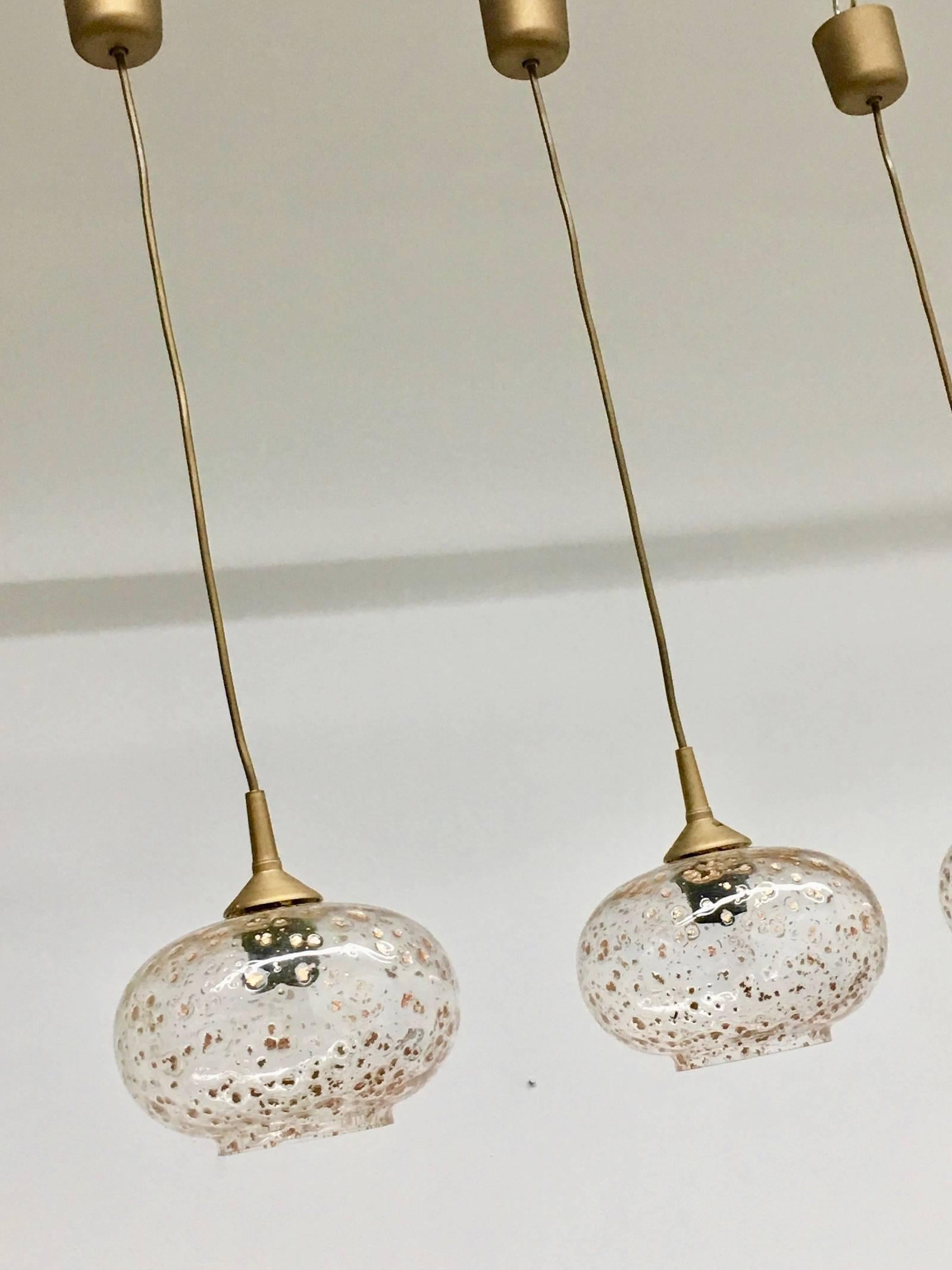 Lot of five beautiful pendant lights, manufactured by Doria Leuchten in the 1960s. Each is made of Plastic hardware with one light source and a gold flaked glass on it. Each is approximate 30 inch in total high. The glass is approximate 5.25 inch
