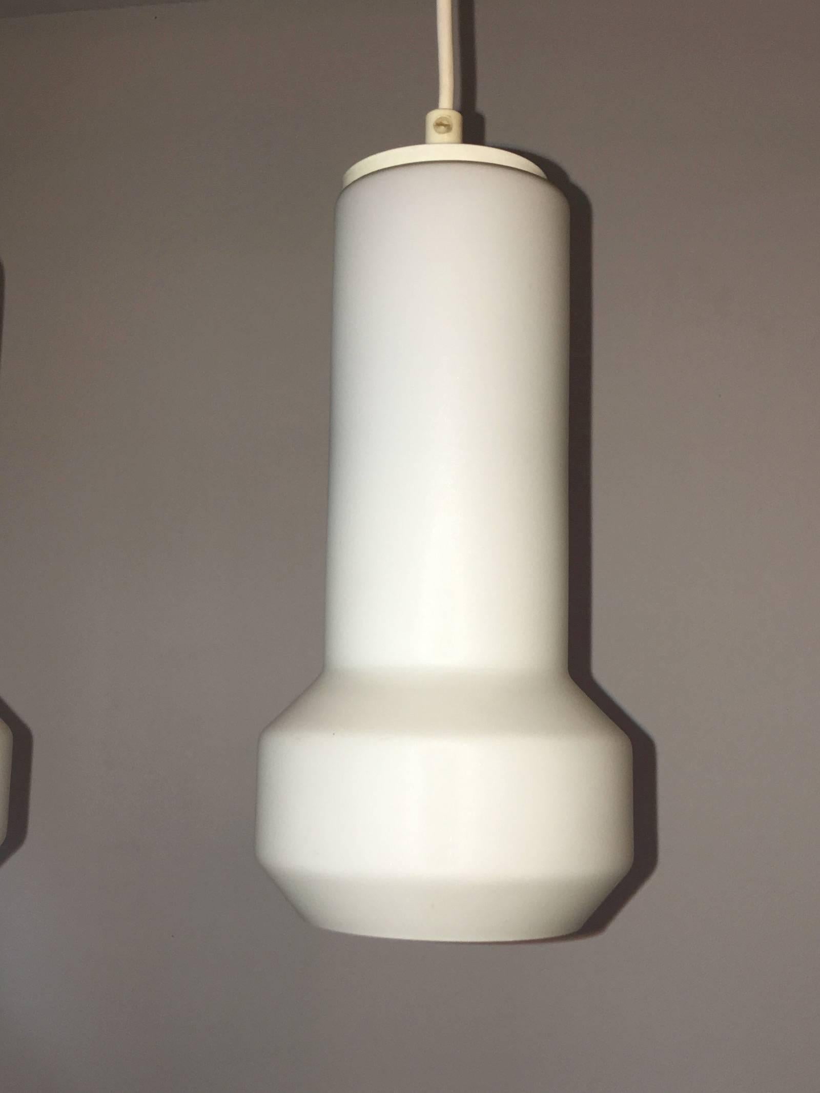 A pair of milk glass lamp pendants by Doria Leuchten, 1960s, Germany. The previous owners had used it as bedside Lamps. Each fixture requires one European E27 Edison bulb, up to 40 watts.