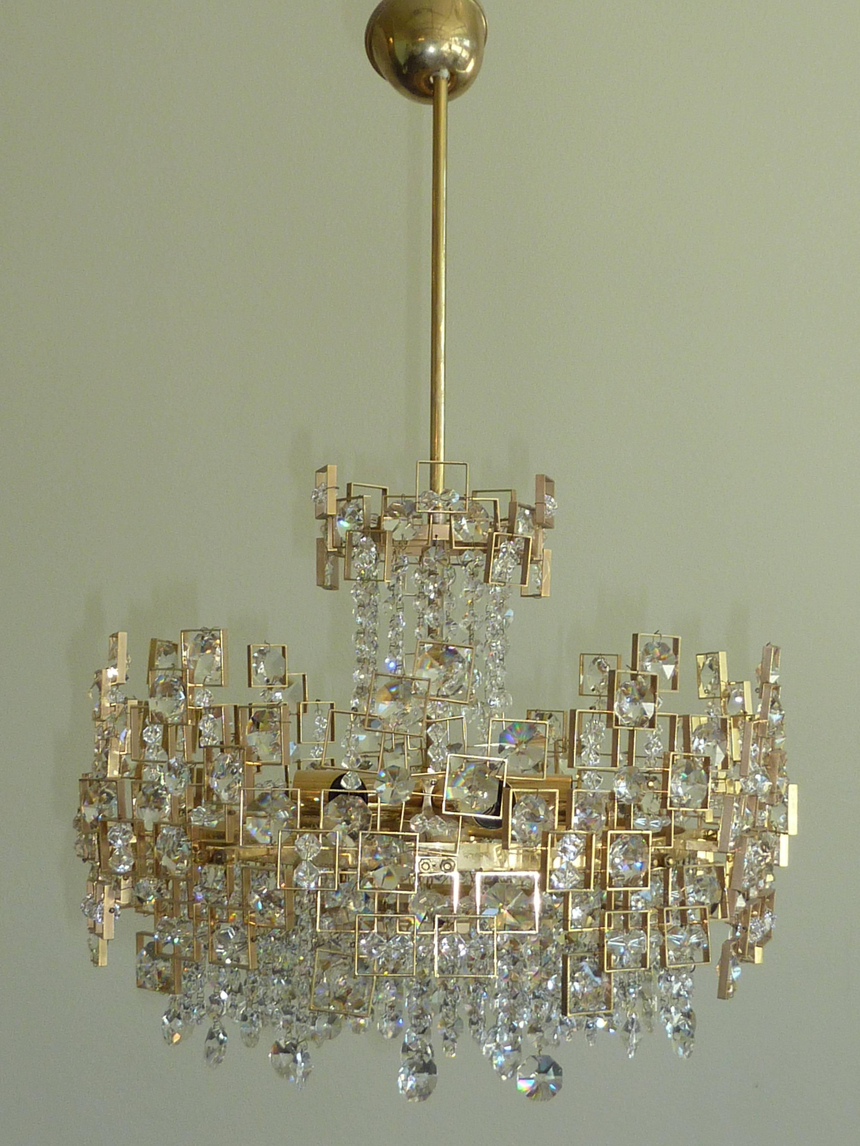 Gorgeous crystal chandelier by Lobmeyr. Large individual "jewels" and hundreds of individual crystals intricately placed among floating geometric brass frame with strings of cut crystals hanging on the bottom and the top. It requires