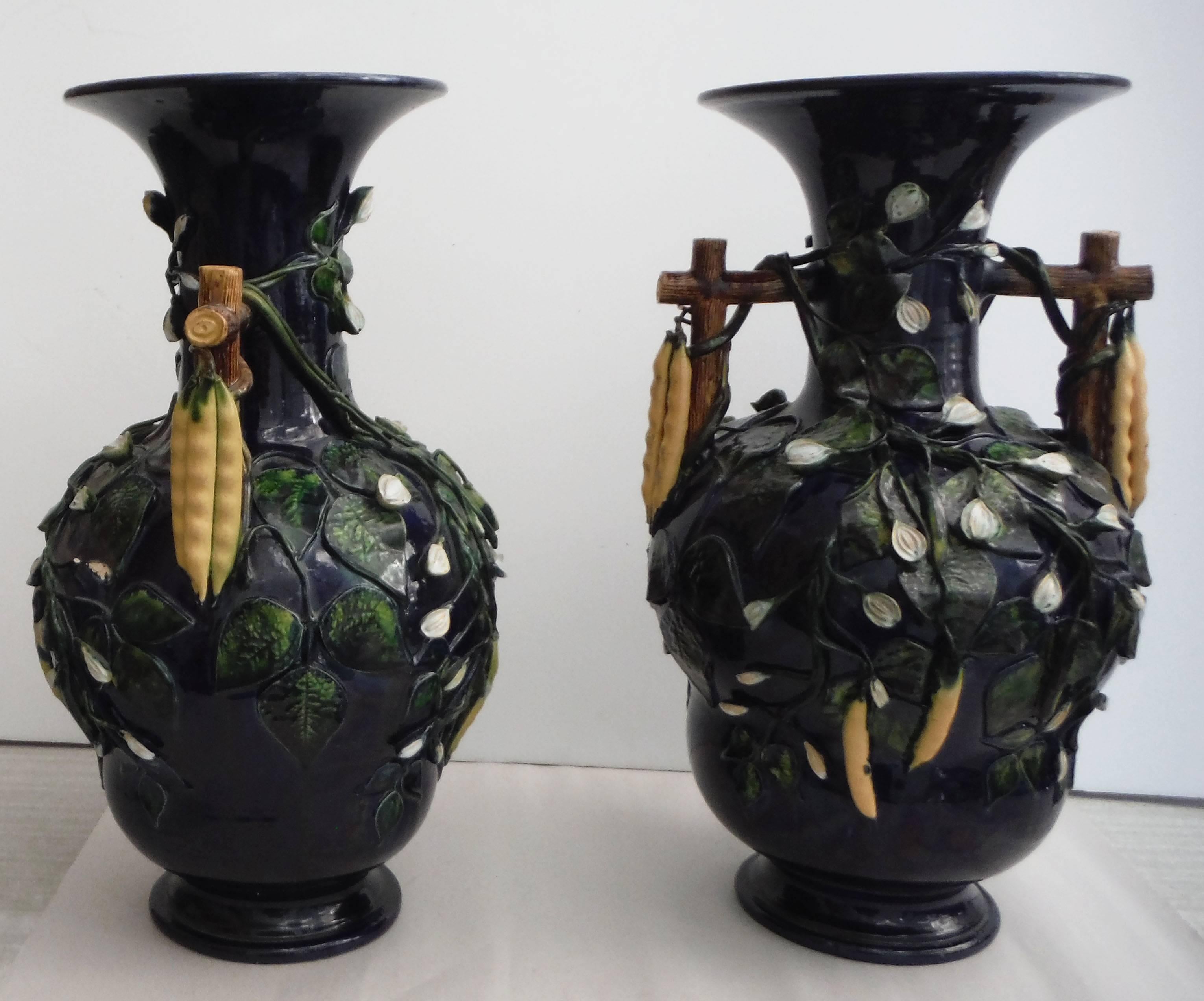 Remarkable oversize pair of Majolica vases decorated with beans in high relief attributed to Saint Honore, circa 1880.
On a deep navy blue, the handled Trompe l'oeil vases are decorated on all the sides with beans and white flowers.