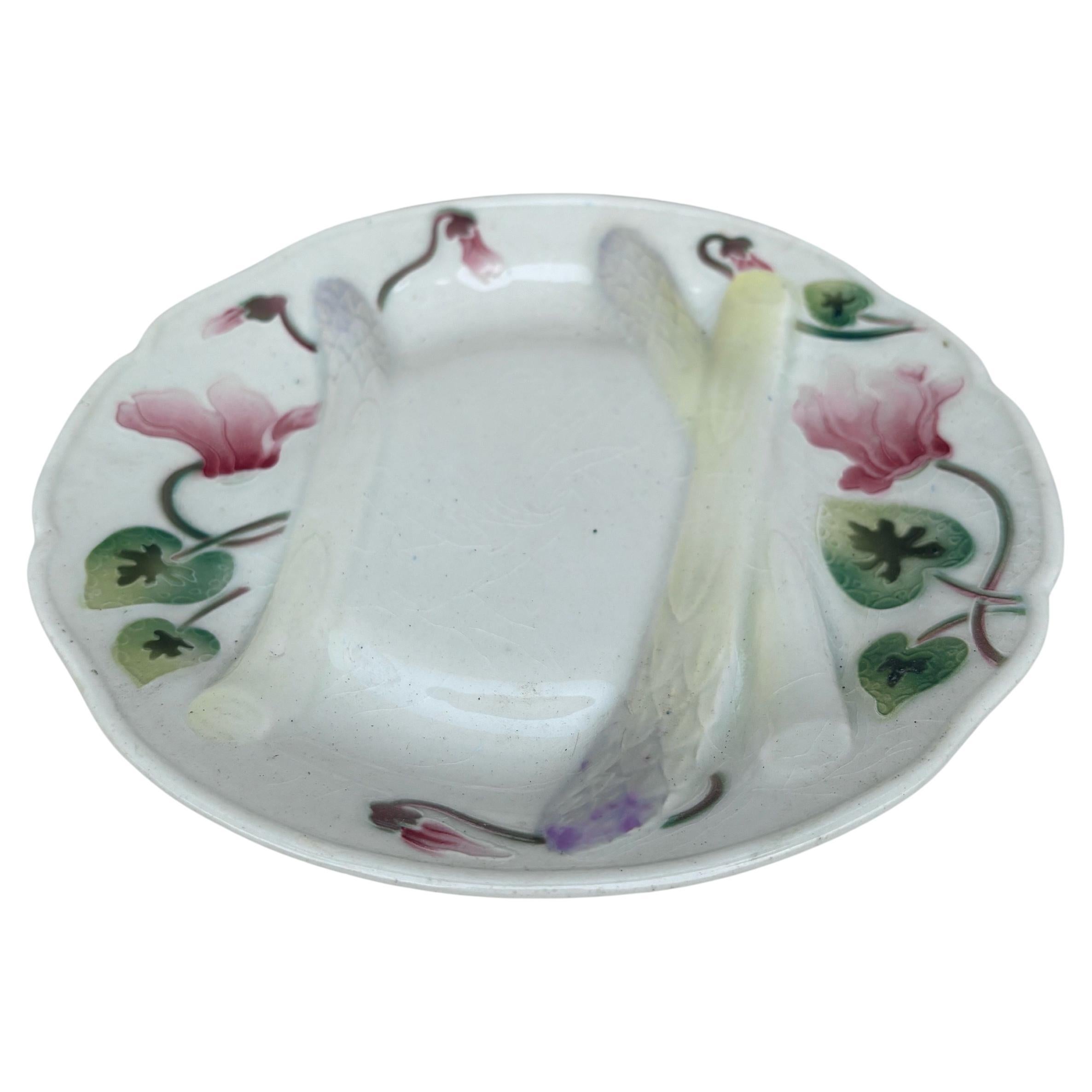 Assiette à asperges en majolique Art Nouveau avec cyclamens signée Keller et Guerin Saint Clément.
Toutes les grandes manufactures françaises produisaient à la fin du 19ème siècle des assortiments d'asperges et d'artichauts.
Référence / 
