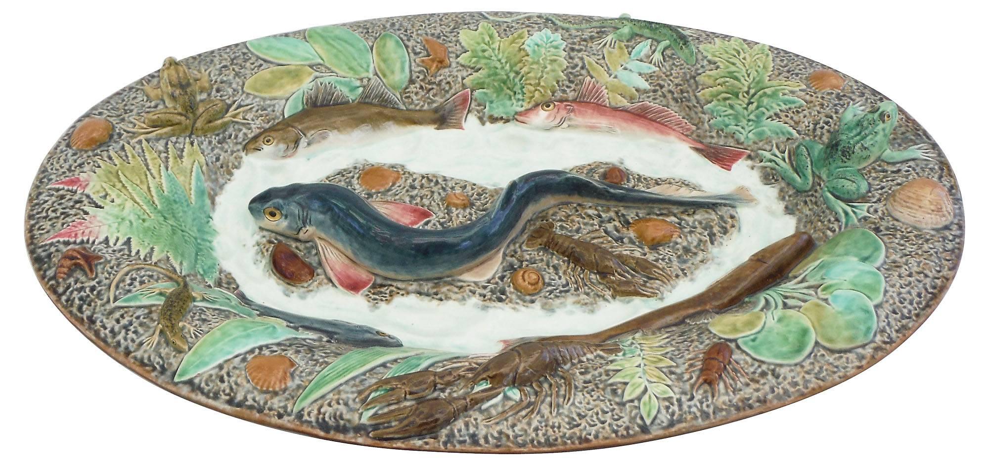 Grand plat mural de Palissy, un grand requin-chat au centre entouré de quatre poissons, deux grenouilles, deux écrevisses, deux lézards, des coquillages et différentes plantes vertes, circa 1900, ce plat est inspiré d'un plat de Thomas Sergent et a