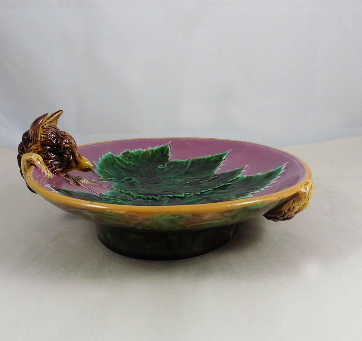 Elegant pink Majolica serving dish decorated with a three green vine leaves, the handle formed as a fox peering into the bowl with its tail appearing on the mottled underside signed George Jones and dated July 1869.
Nice example of the Naturalism in