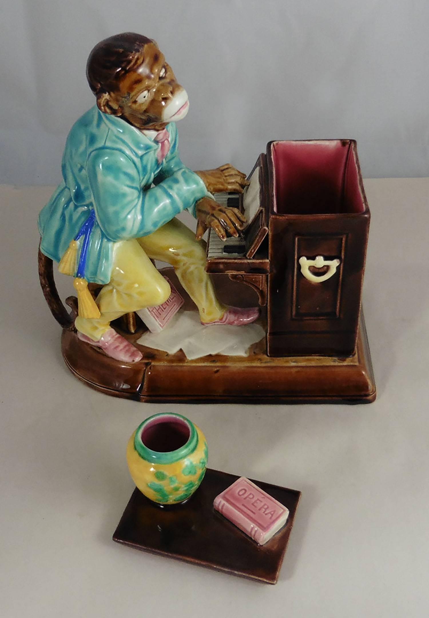 Amusing Majolica monkey pianist tobacco jar signed Sarreguemines, circa 1880.Rarely found complete with his lid the chimpanzee wear a costume of Oriental style, he play piano and two books are represented with the titles
