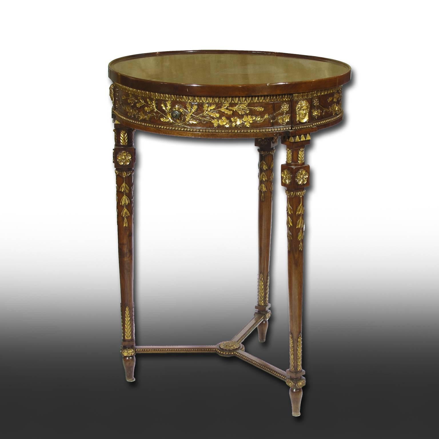 A small circular Louis XVI solid walnut wood table with three slender legs and one drawer.
A refined gilt foliage frieze adorns the tabletop and the legs.
An elegant piece of furniture, beautifully carved and polished with shellac.
Central Italy,