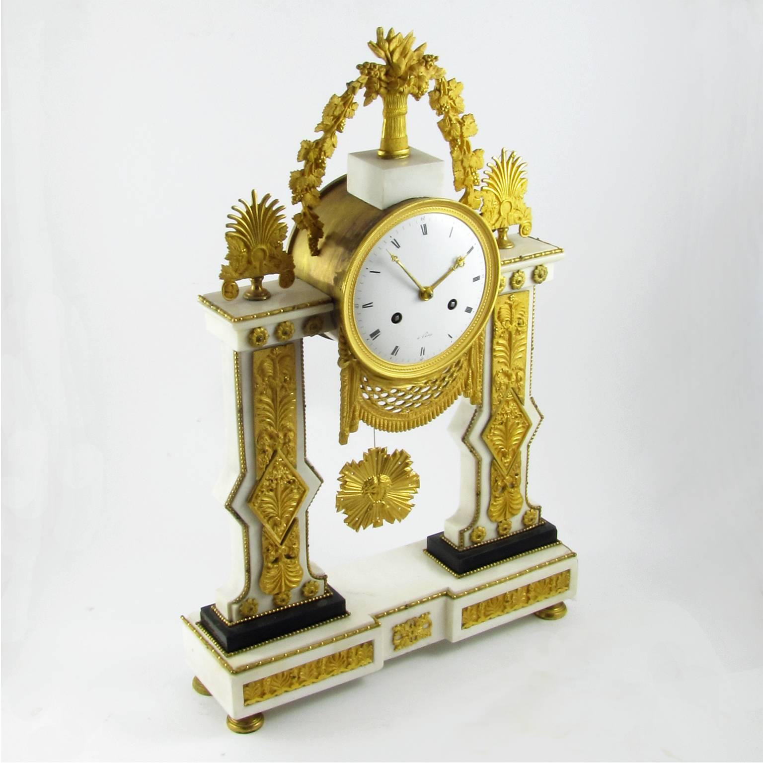 A rare white marble and ormolu gilt mantel clock with a beautiful architectural structure. The large marble base on circular bronze feet is surmounted by two lateral pilasters with classical style decorations, friezes and potted flowers. Circular