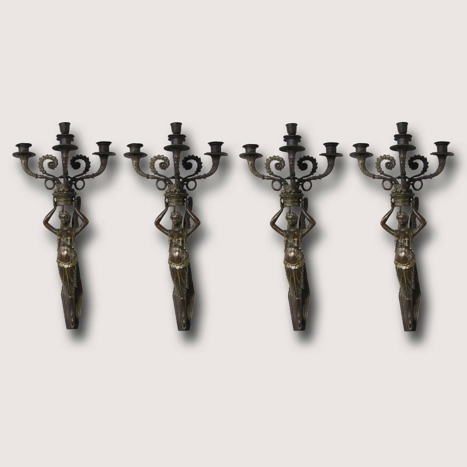 A beautiful set of four figural three-light patinated bronze sconces.
A winged female figure is holding the three candle arms above her head.
Signed on the back plate ‘Fisher’. 
English manufactory from the late 19th century.
 
