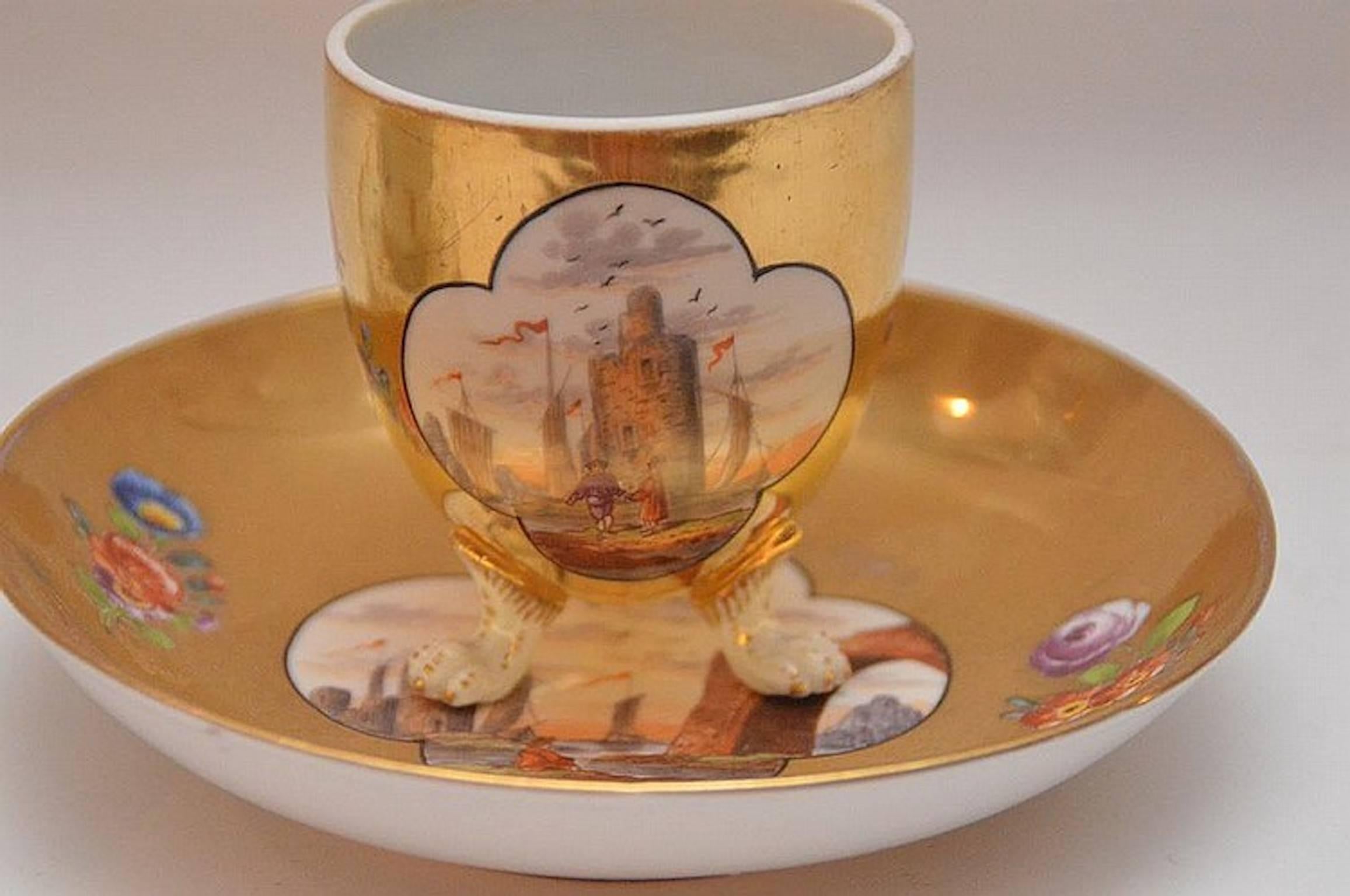 Hand-painted seascape scene on a gilt ground.
Measures: cup 2.75 in W x 3.13 in H
saucer 6.13in W x 1.25 H.
 