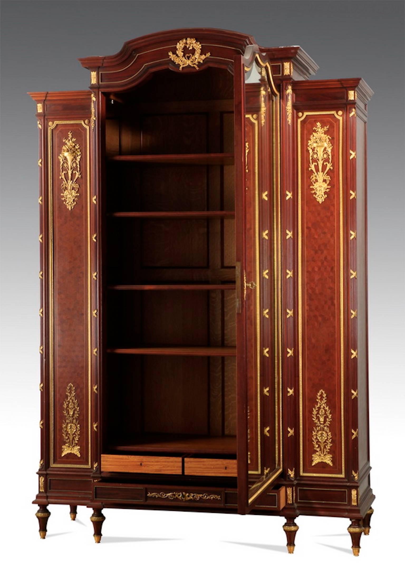 Fine 19th century French gilt bronze-mounted, parquetry inlaid armoire with shaped pediment and central beveled mirror, the single door opening to a fitted interior with coffered back and molded edge shelves, above two small interior drawers, the