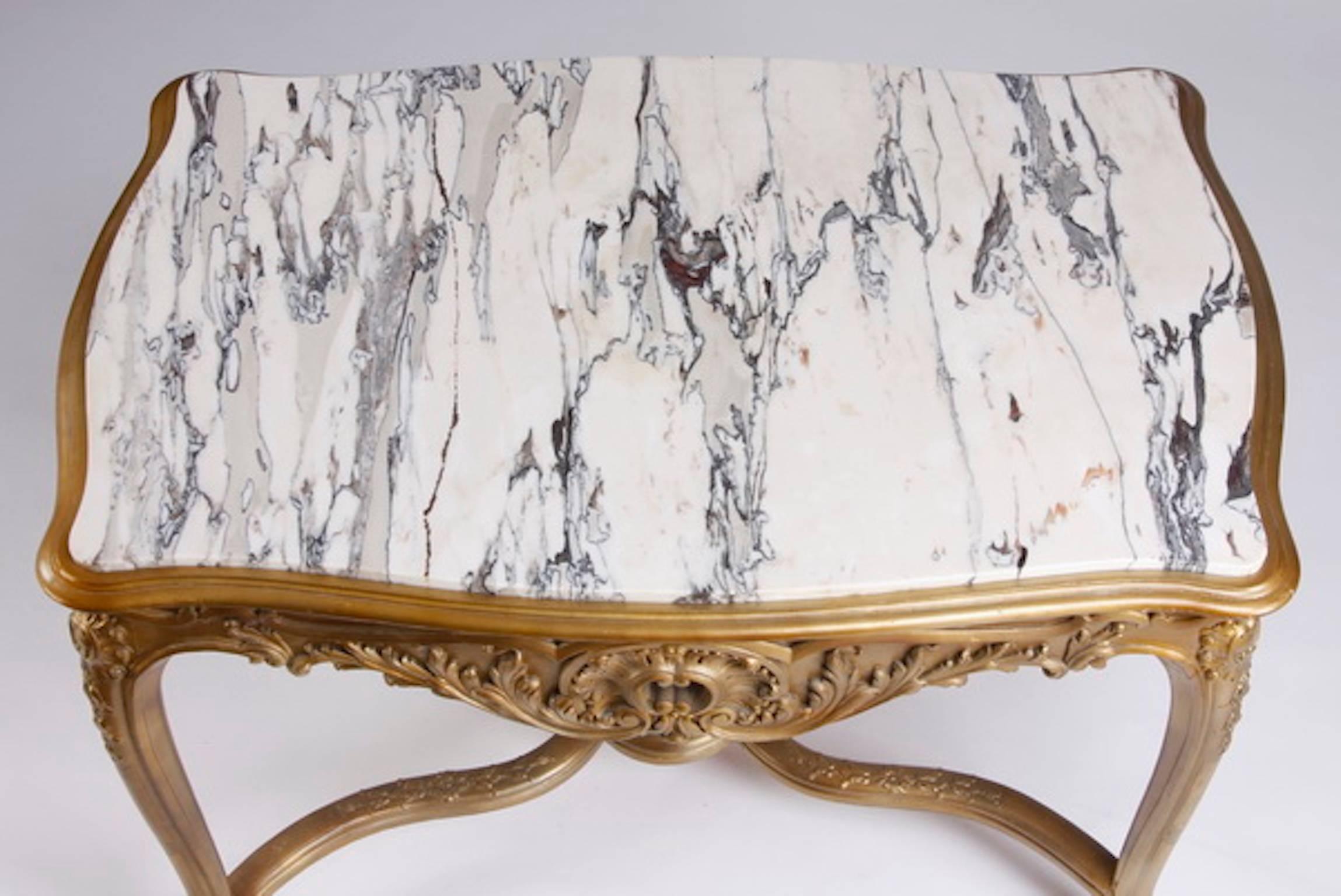 Carved giltwood marble top center table, the apron with central C-scrolls issuing acanthus details, raised on cabriole legs joined by a serpentine stretcher with a central rosette patera, 31