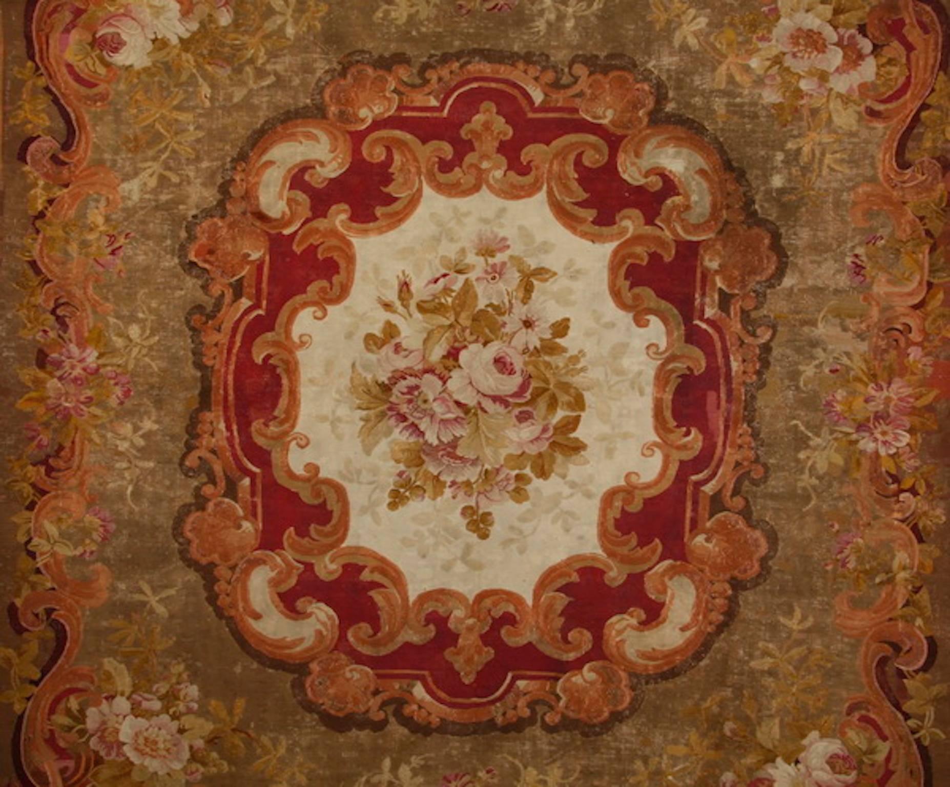 Early to mid 19th century French hand knotted wool carpet, depicting a central shaped medallion formed with C-scrolls encircling a floral bouquet, against a solid ground further framed with a scrolling border interspersed with flowers, 113