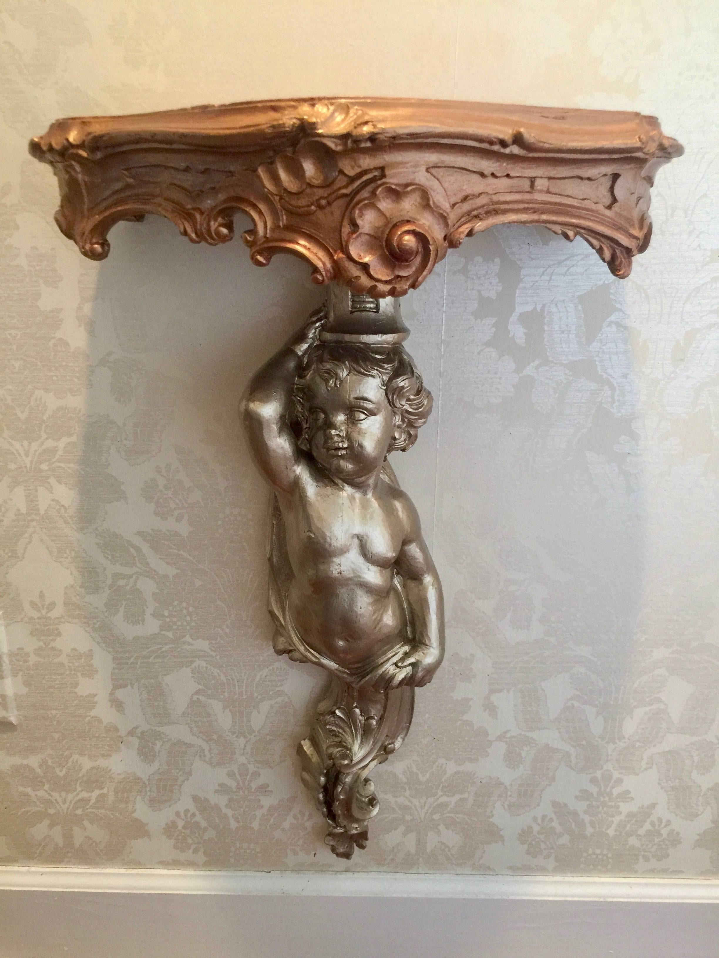Pair of Louis XV style carved giltwood wall brackets bronze and gold in color with putto and scrolls.