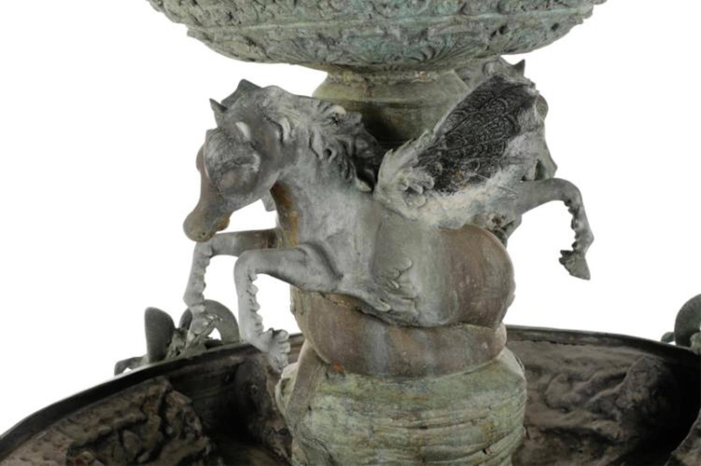 Italian, 20th century. A large Rococo style bronze garden fountain with an all-over verdigris patina, having two tiers, the upper with a putto riding a grotesque dolphin, supported by two intertwined Pegasus figures, the lower tier gadrooned and