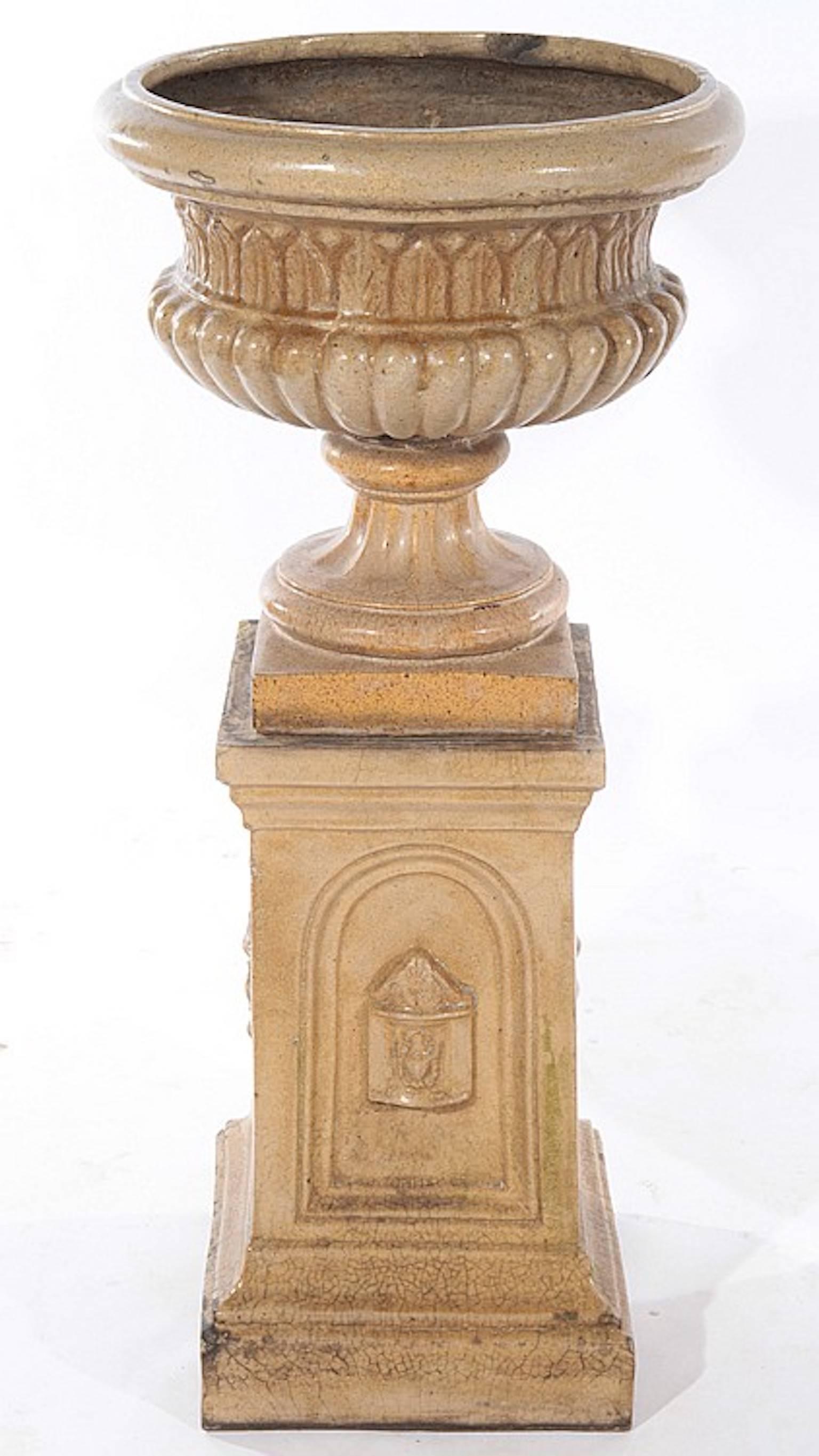 A pair of 19th century glazed terracotta garden urns resting on stepped pedestal form bases.