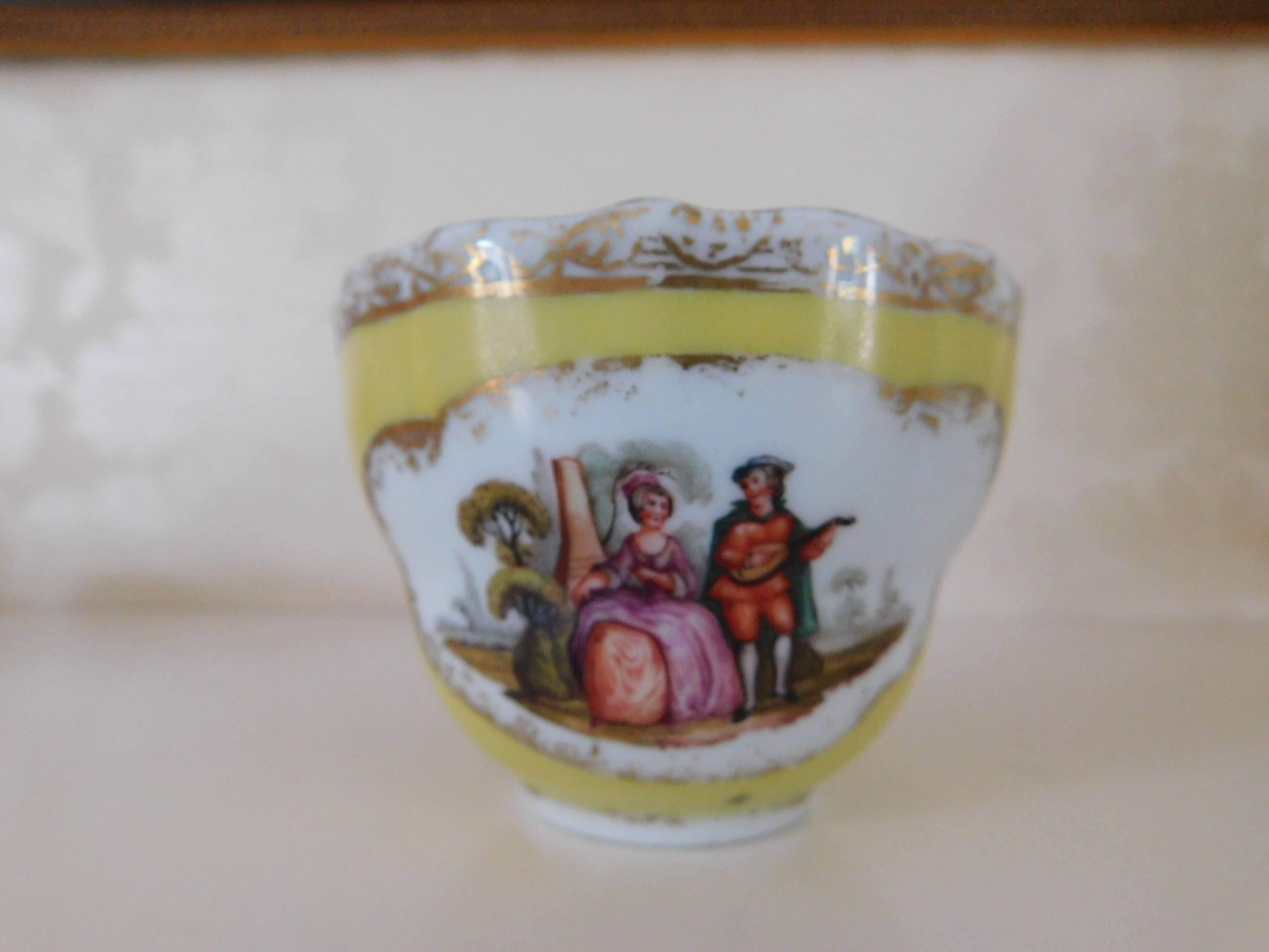 19th century, Meissen Porcelain cup and saucer
Yellow with painted scene of a man and woman

Measurements in inches:
Cup 3.38 D x 2.5 H
Saucer 5 D x 1.5 H.