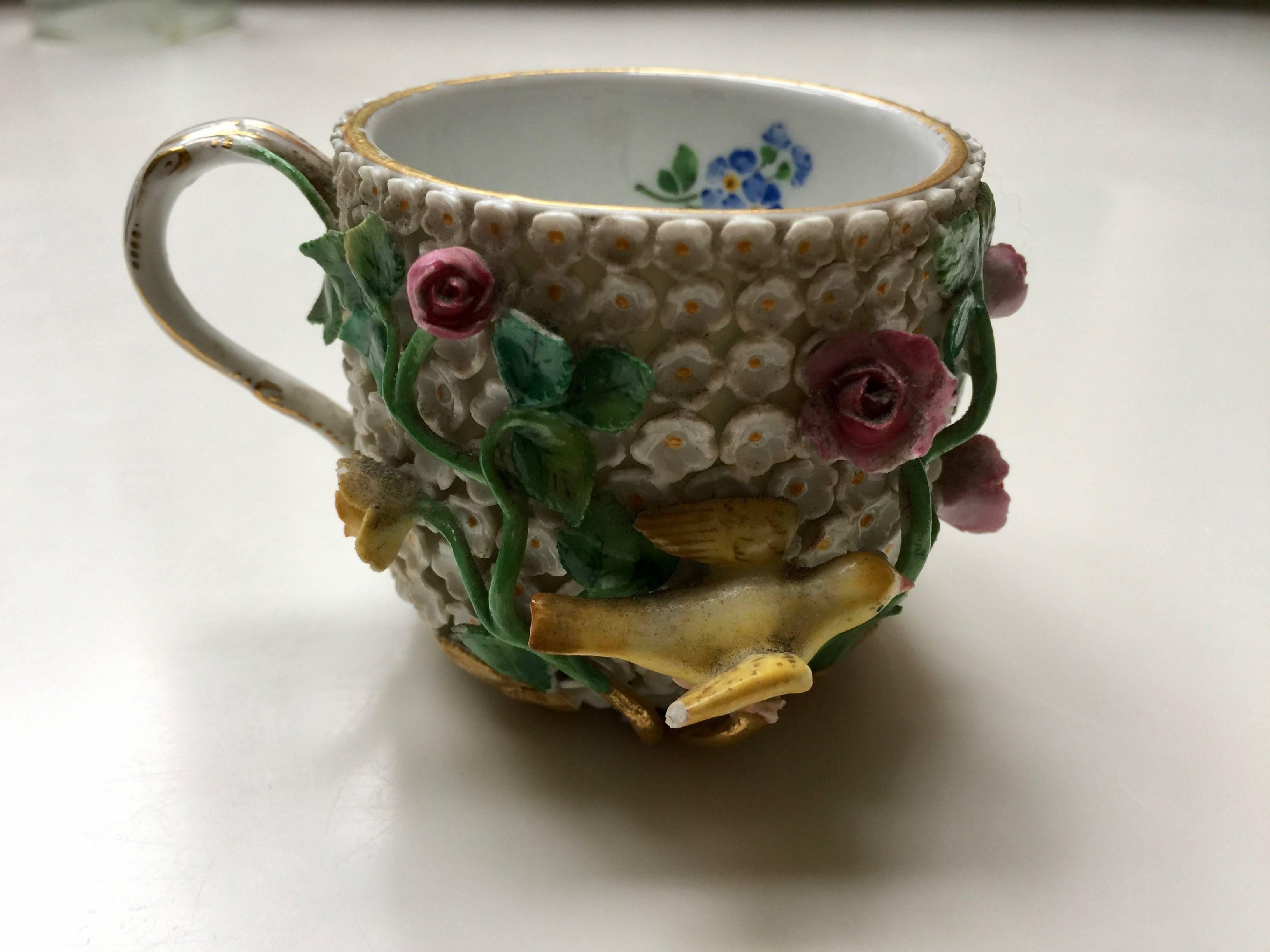 Meissen schneeballen cup and saucer, applied with flower heads throughout and yellow birds perched amongst scrolling foliage, underglaze blue crossed swords.

Measurements in inches:
Cup 2.5 D x 2.25 H
Saucer 5 D x 1.25 H.