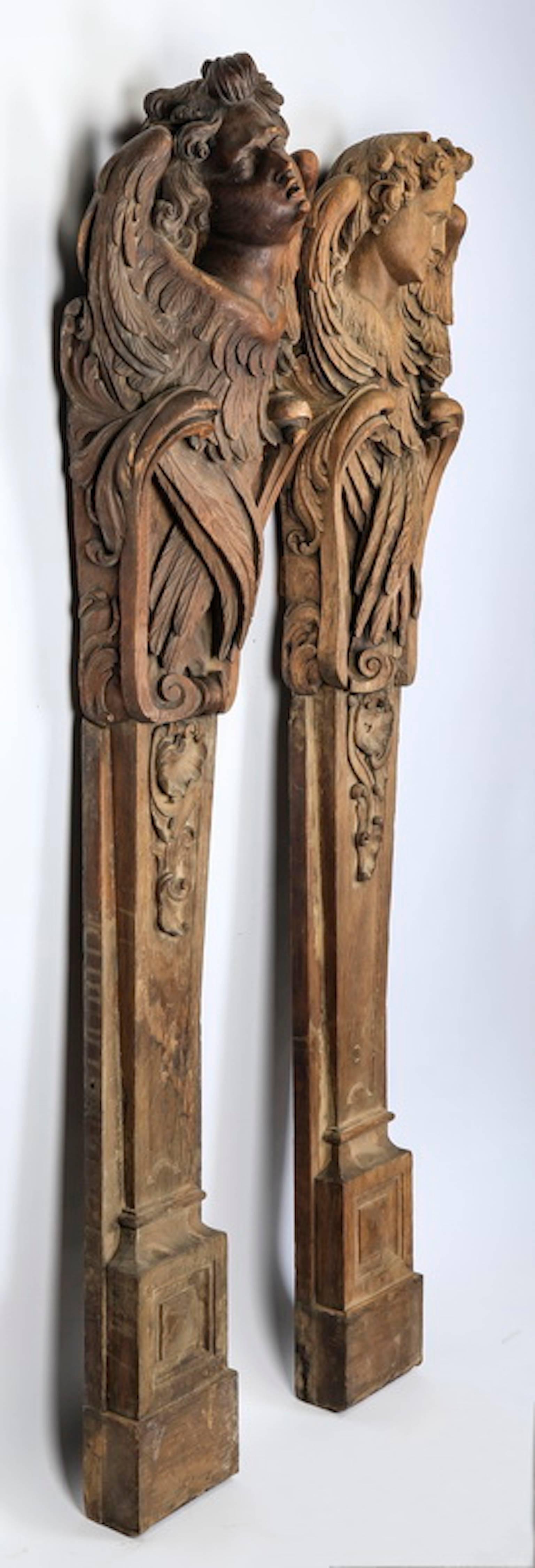 Pair of French carved oak archangel term pilasters in the Baroque taste, late 18th century, each angel with a realistically carved face above crossed wings captured in 'C' scrolls ending in volutes, surmounting tapering pilasters decorated with