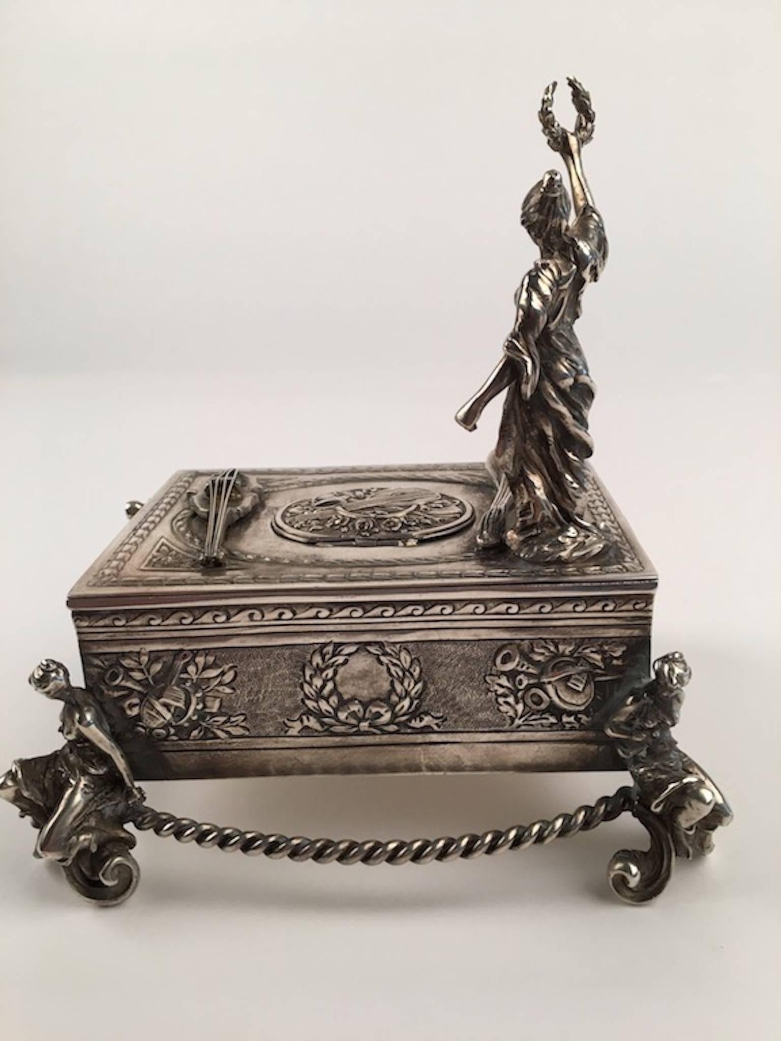 925 silver bird box with a lady holding a wreath. 
When the knob is pulled the lid lifts and a bird appears and tweets a song.