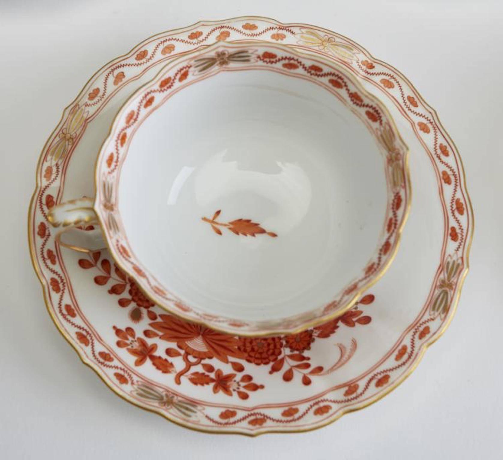German Meissen porcelain dessert service in the Red Indian Painting pattern. Set has Neuer Ausschnitt shaped rims accented with gold highlights. The coffee pot lid has a stylized rose knob. Each piece bears the Meissen crossed swords mark in