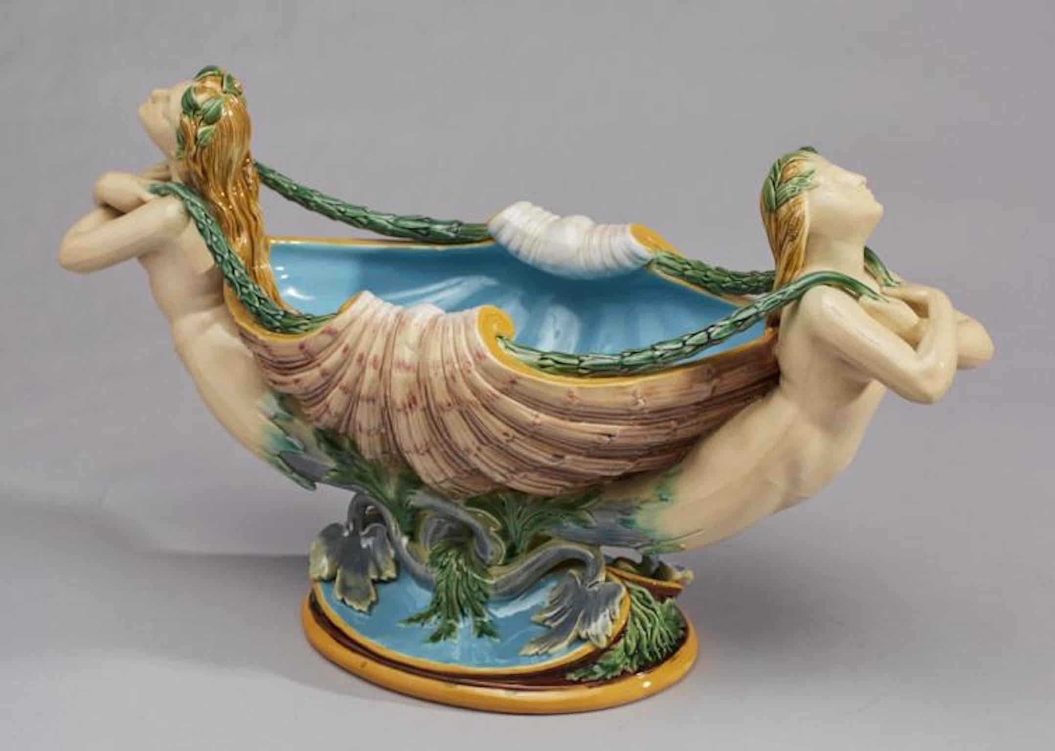 Fine 19th century Minton English Majolica centerpiece is entitled, flower bearers, shape No.1182, and likely designed by Albert Carrier Belleuse. Modeled as a scallop shell flanked by mermaid supports, their hair applied with lily-pads and spilling