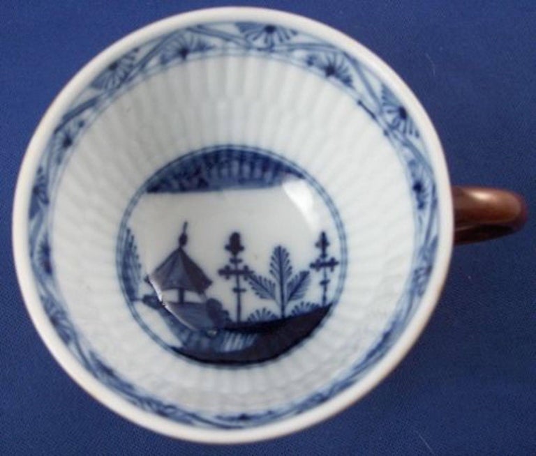 Rare cup and saucer made by Meissen in the 18th century. Both the cup and saucer have a hand painted under glaze blue design related to the straw flower design with an addition of a scene in the center including buildings and plants. They both have