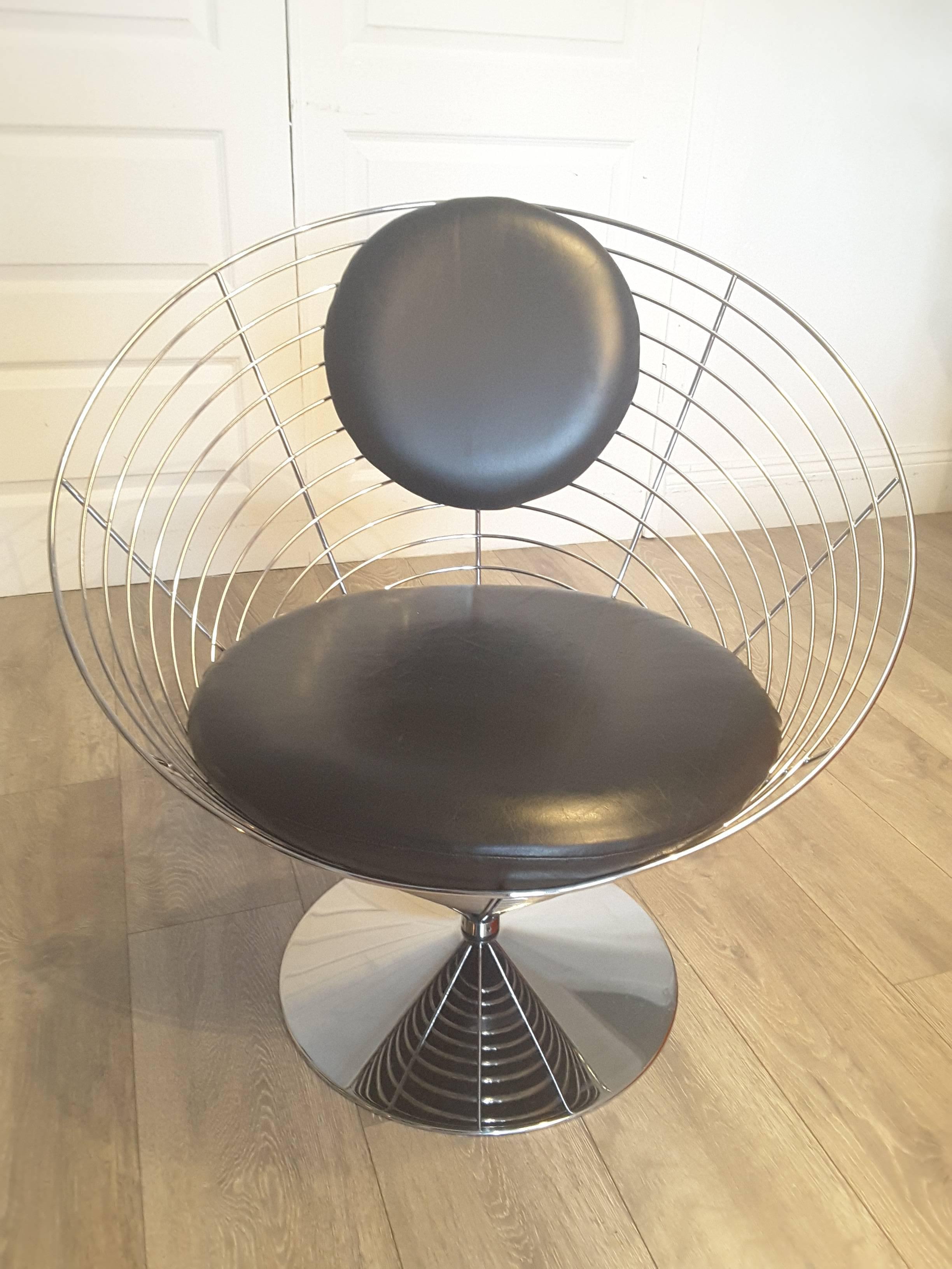 A wire cone chair designed by Verner Panton for Fritz Hansen. Constructed from one coherant spiral welded into eight struts. On swivel base with black leather upholstery.
