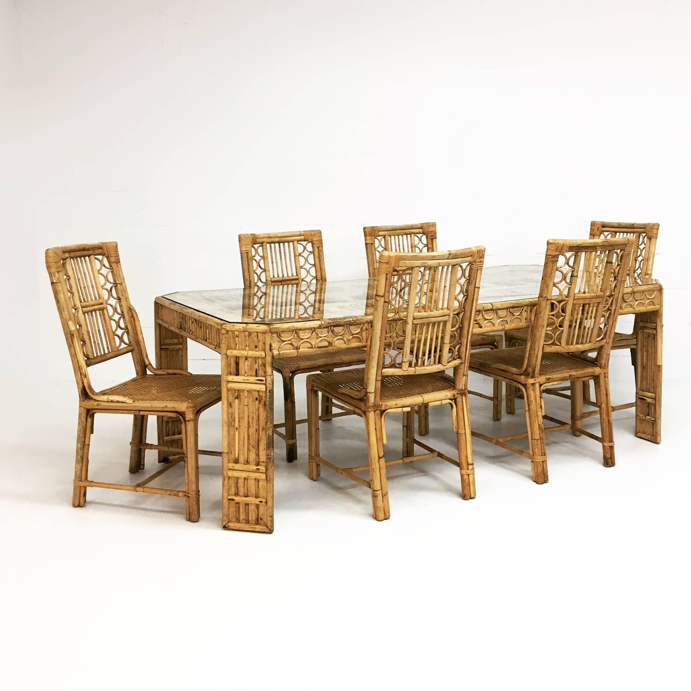 A rare Mid-Century glass topped rattan and bamboo dining table with six chairs. Age appropriate wear. All chairs will be delivered newly caned. 
Measures: Table 42 D x 84 W x 29 H.
Chairs: 23 D x 20 W x 38 H, seat 17" H.