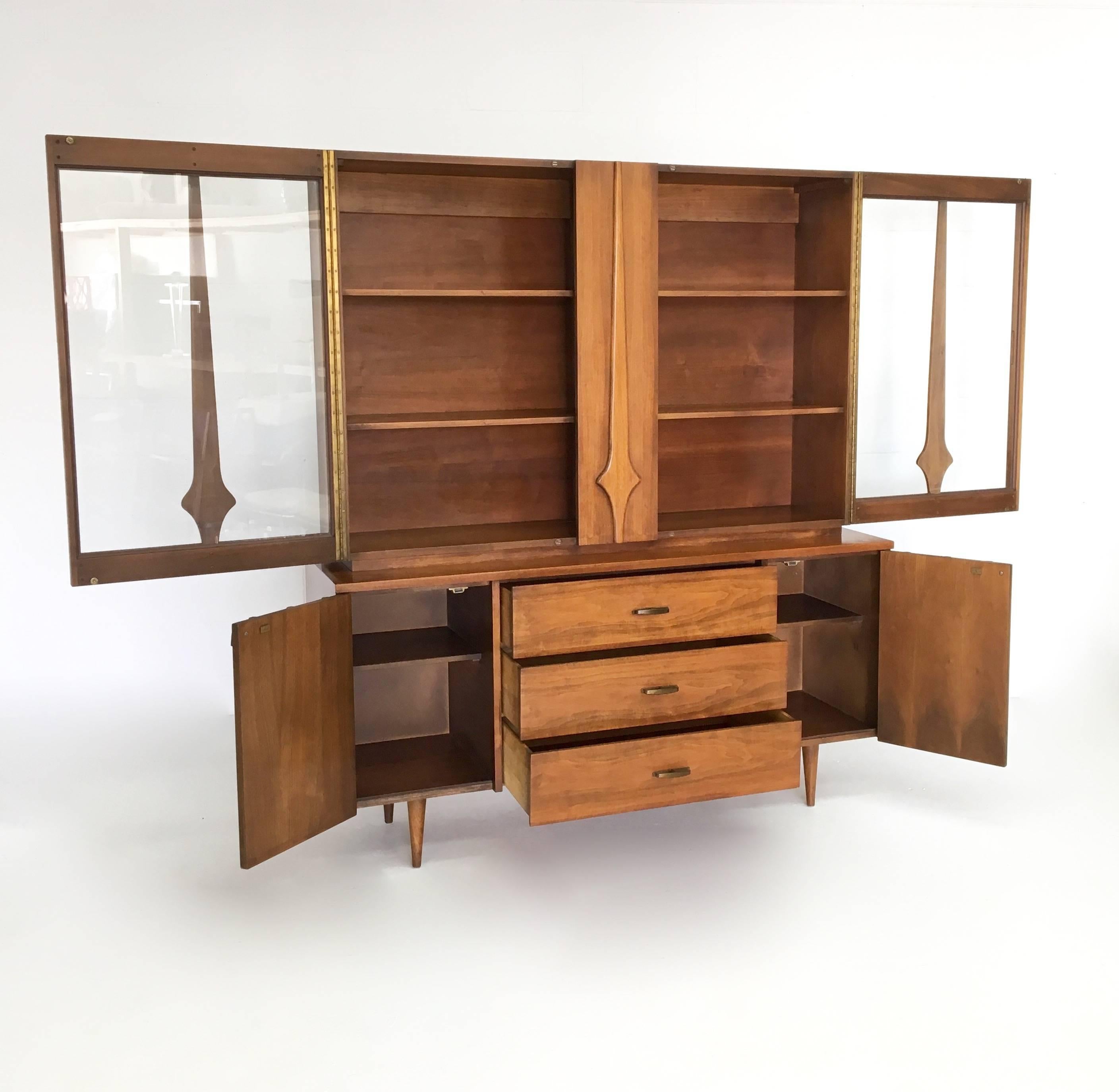 A wonderful Mid-Century Modern sideboard and Hutch in the Brasilia style. Upper hutch has three shelves with two glass fronted doors. Sideboard, bottom section, has three drawers and two cabinets with two shelves inside each. Age appropriate wear.