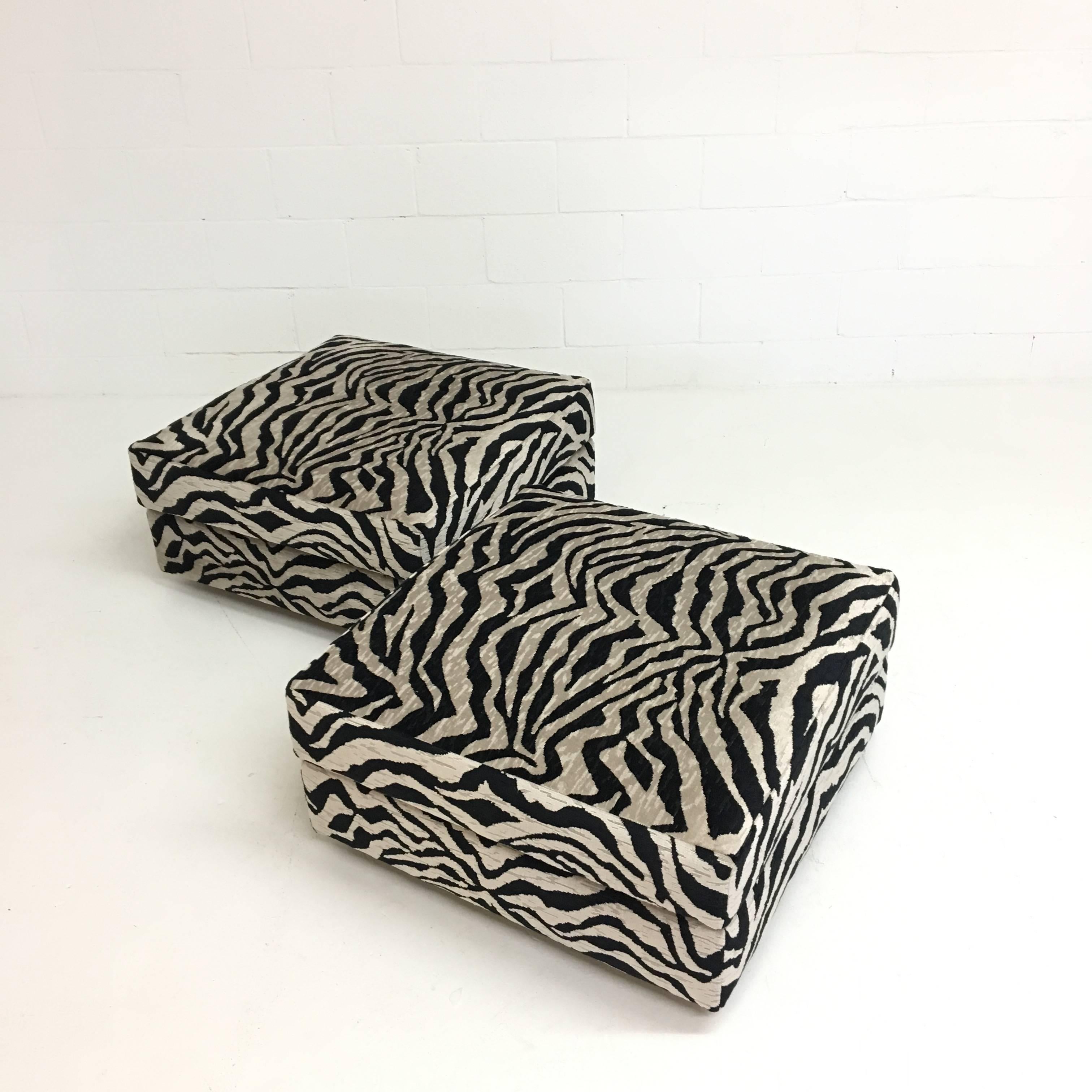 A pair of Mid-Century ottomans that have been reupholstered in a graphic zebra print velvet in gray and black. Each item is set on four casters for easy moving.