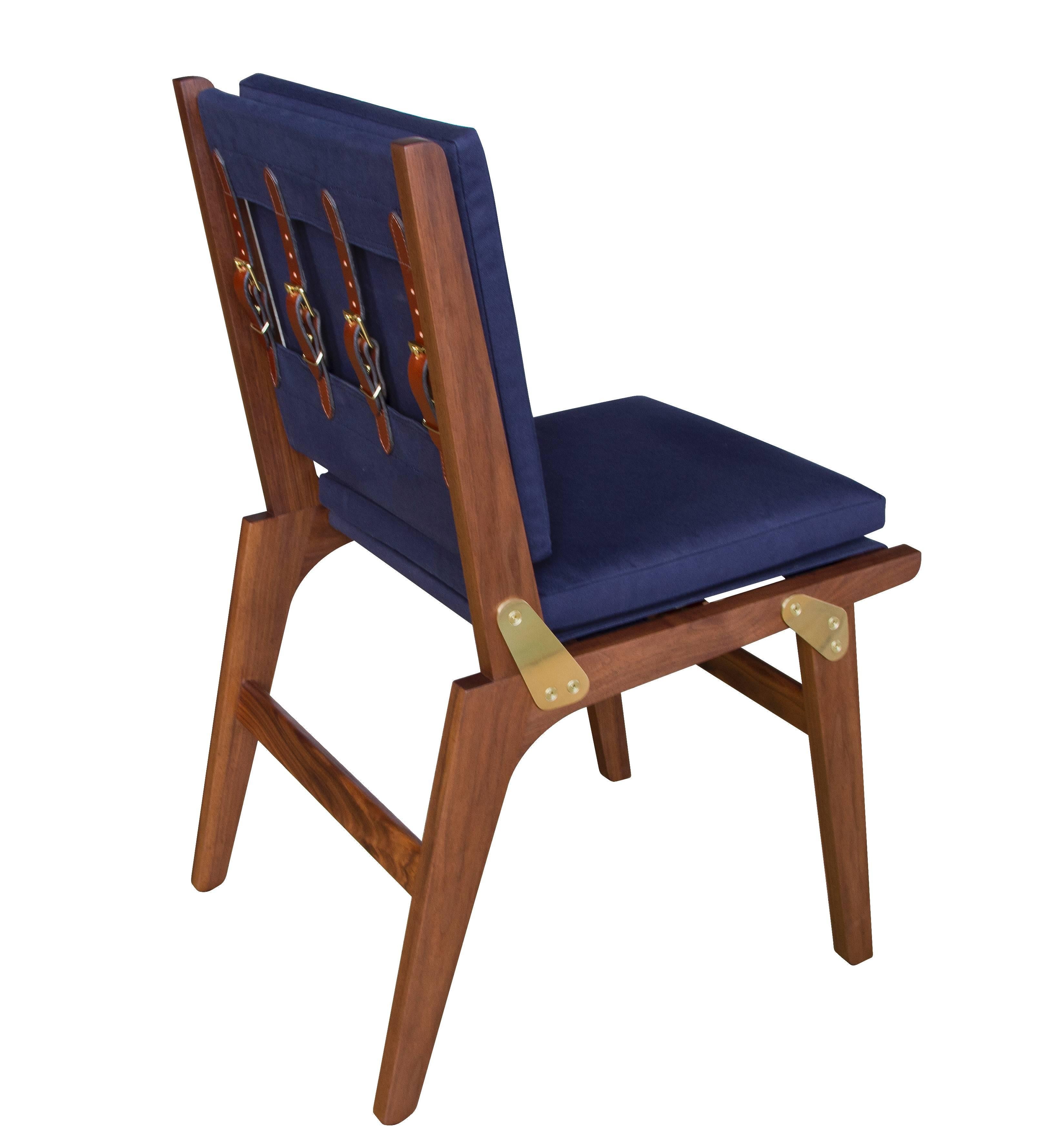 The Officer's Field Set dining chair in oiled walnut with navy canvas upholstery, saddle English bridle leather strapping and natural brushed brass buckles and hardware. Shown as the non-folding version. Available as a folding chair for an upcharge