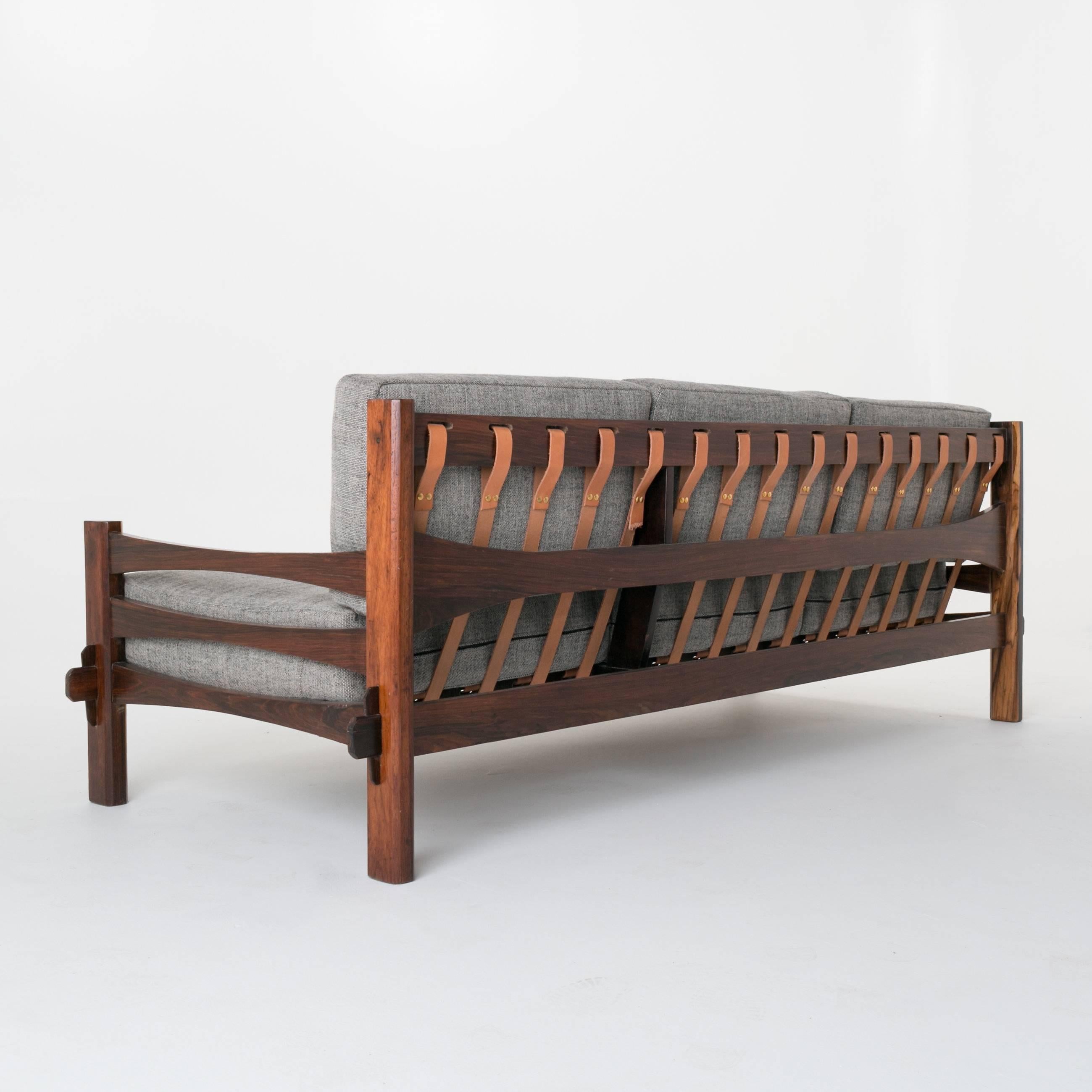 Simple Brazilian rosewood sofa. The decking in the sofa has been done in leather straps. The sap grain from the rosewood is exquisite. 

In order to preserve our inventory, after restoration we blanket wrap and store nearly every piece in our