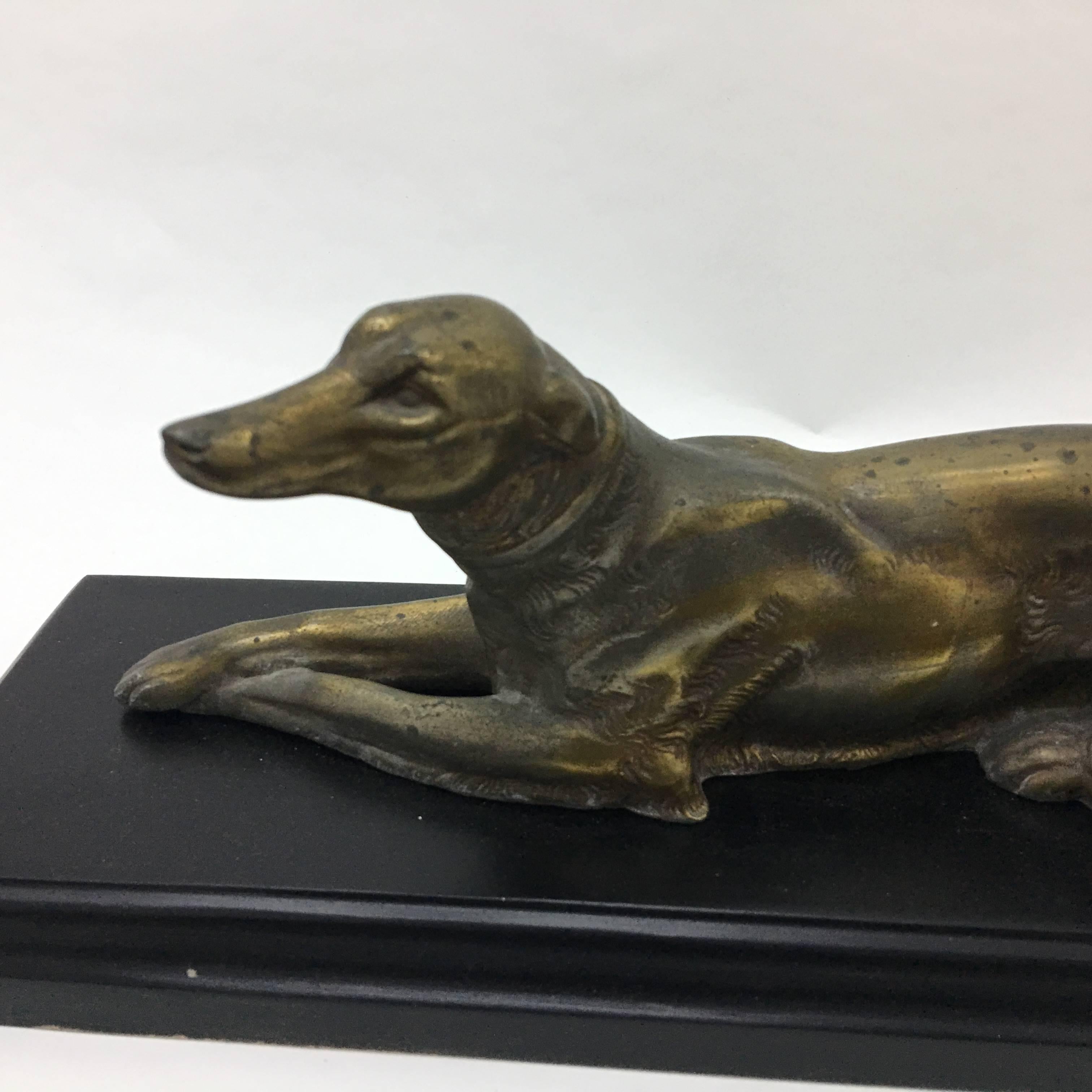 A metal statue of a greyhound on a black wood base made in France.