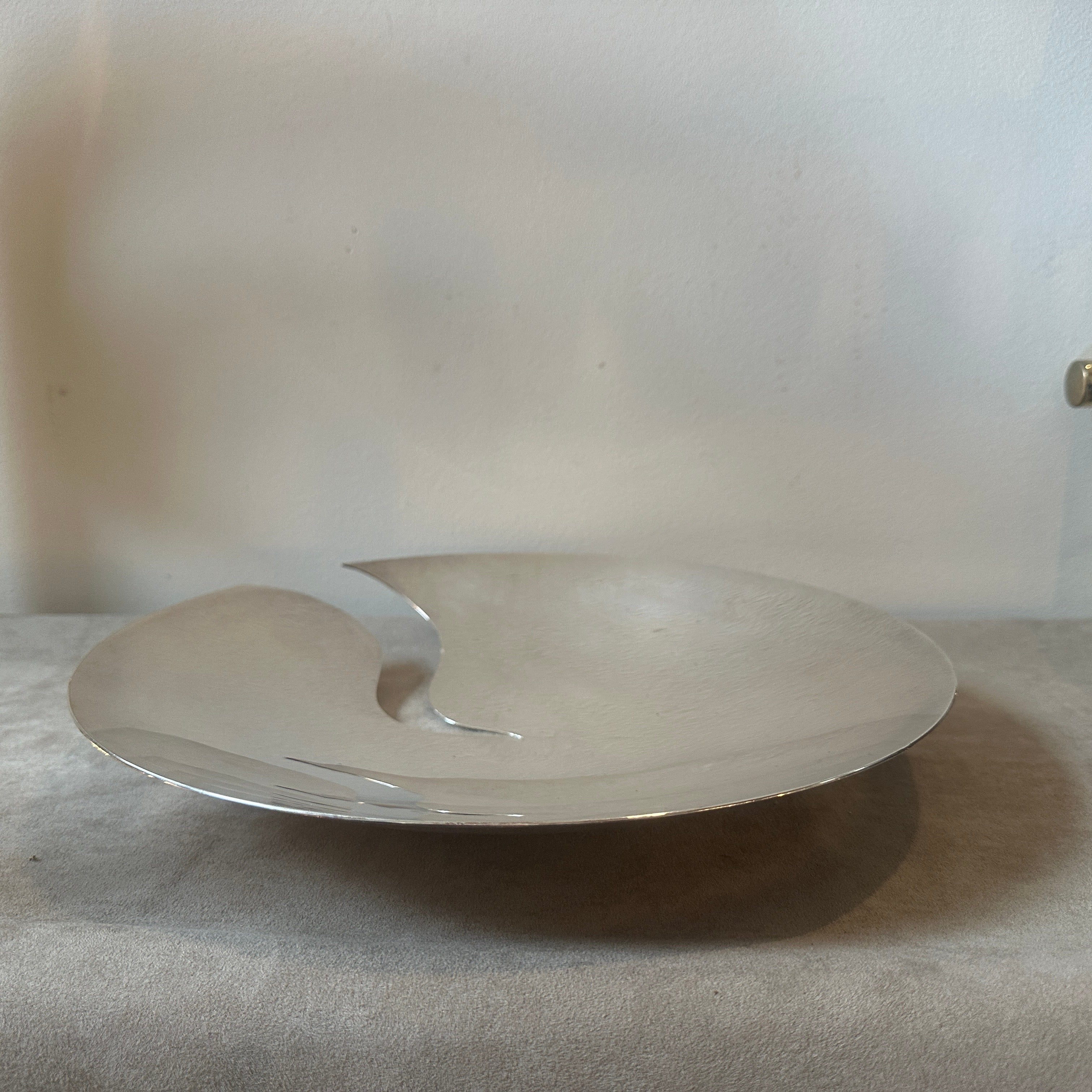 Un icónico centro de mesa redondo plateado diseñado por Francesco Bettoni y fabricado por Mesa Italia en los años noventa, está marcado en la parte inferior y en buen estado en general. 
En 1980, Giuliano Malimpensa funda Mesa. Tras trabajar con Gio