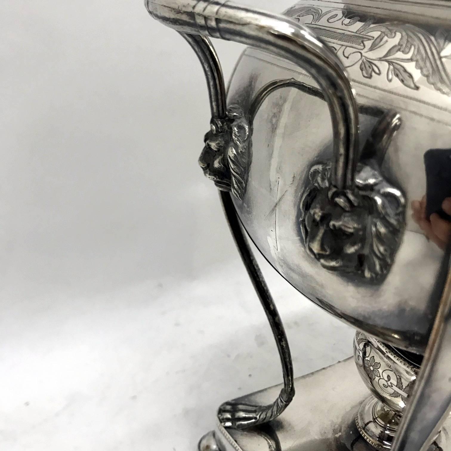 Elegant and graceful samovar (or tea urn) in Old Sheffield Plate, the body is smooth but at the top has delicate floral engravings and is supported at the rectangular base with stylized lion paws, the smooth handles are soldered to the body with