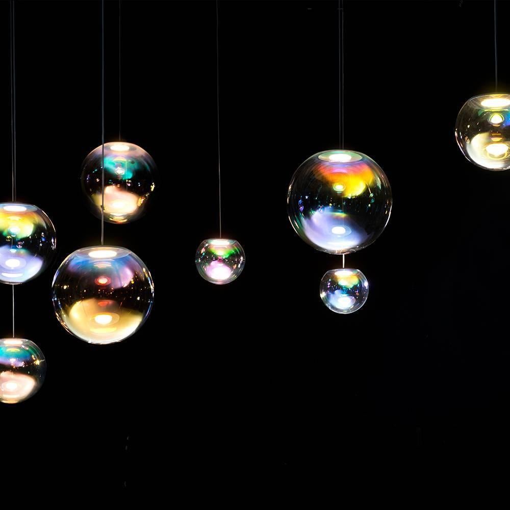 The Iris pendant light appears like a permanent iridescent soap bubble. It is the result of ambitious craftsmanship and technological innovation. An OLED module provides both the light source and mount, with an iridescent film creating the