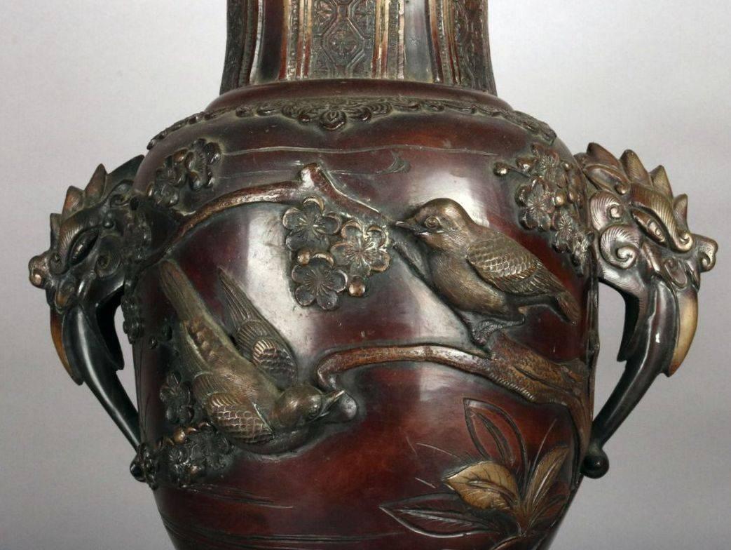 20th century, Japanese figural bronze electrified oil lamp features figural aviary and floral decoration with double handles, Duplex burner and frosted shade atop a ming tree footed base.