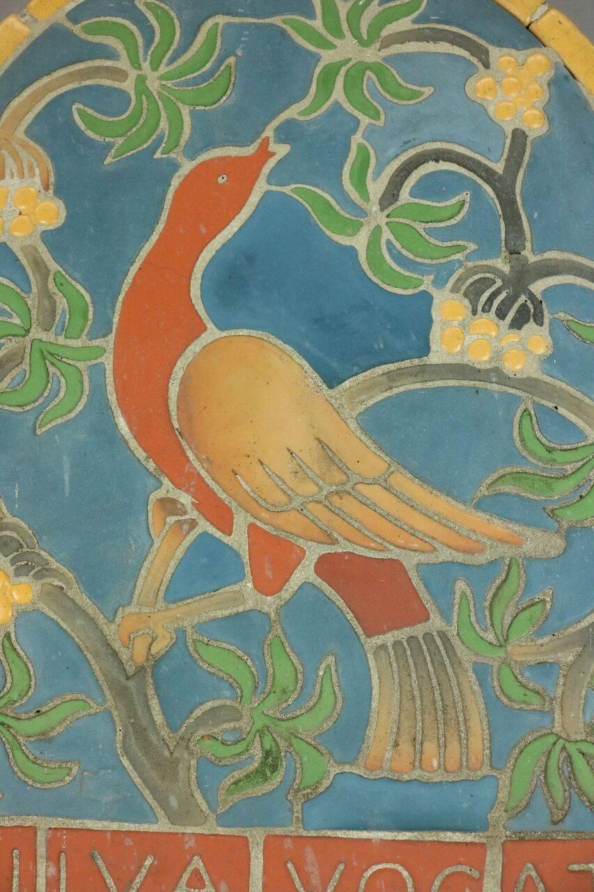 Terra cotta mosaic plaque by Henry Mercer of Moravian Pottery & Tile Works depicts a bird and foliage and reads 
