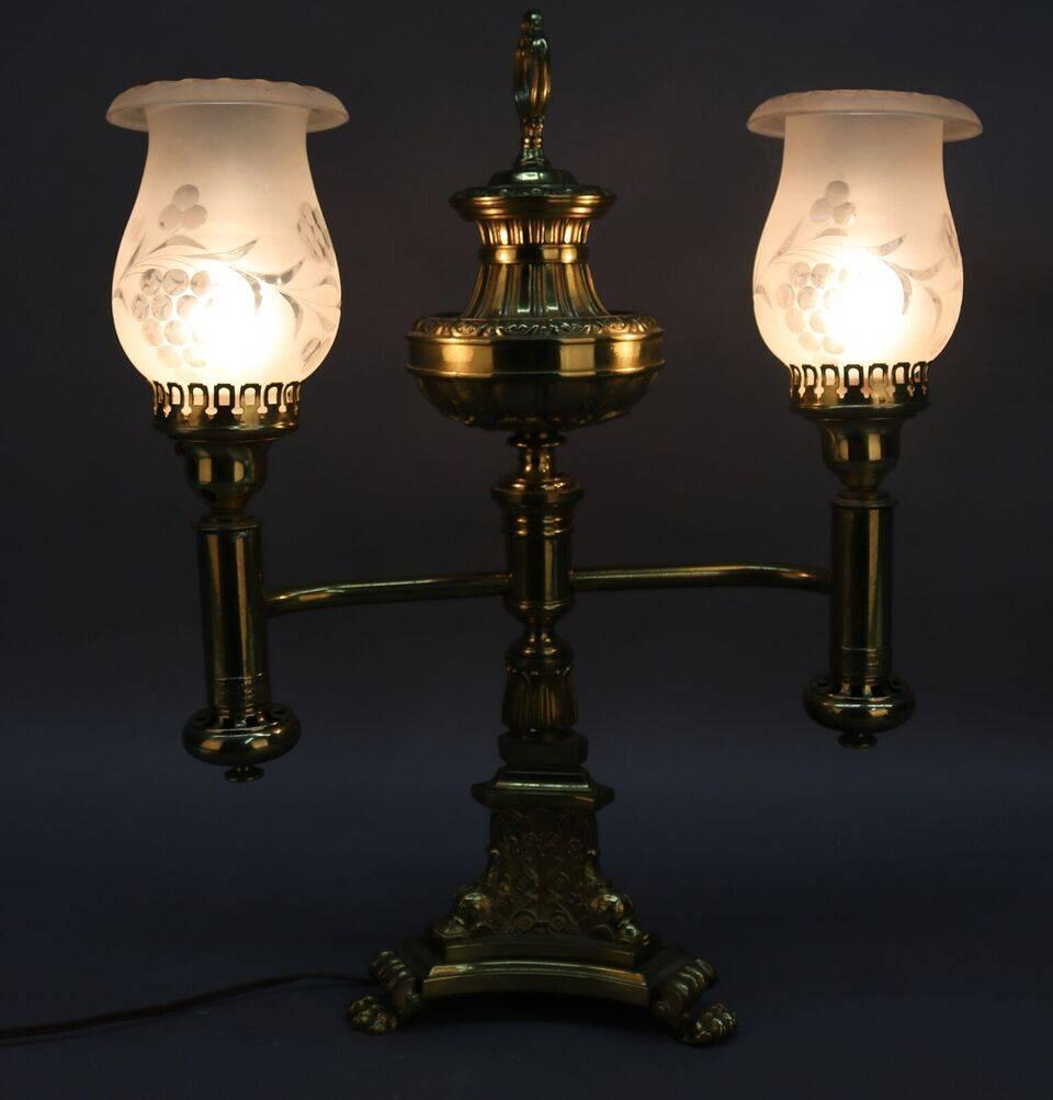 Bronze electrified Astral Argand lamp by B. Gardiner features double light emerging from an urn shaped font resting on three paw feet, with replaced shades, circa 1840. Reminiscent of a solar or sinumbra lamp.