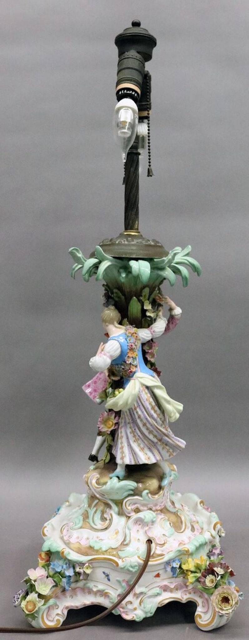 Late 19th century Meissen Porcelain figural lamp base and stand features courting couple around floral decorated tree, classic crossed swords maker mark on base.