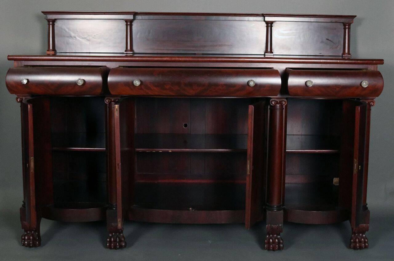 Remarkable antique book matching flame mahogany sideboard features three bow front doors opening into lower compartments, three upper drawers and four classical full columns terminating in massive claw feet, circa 1890. Piece was originally owner by