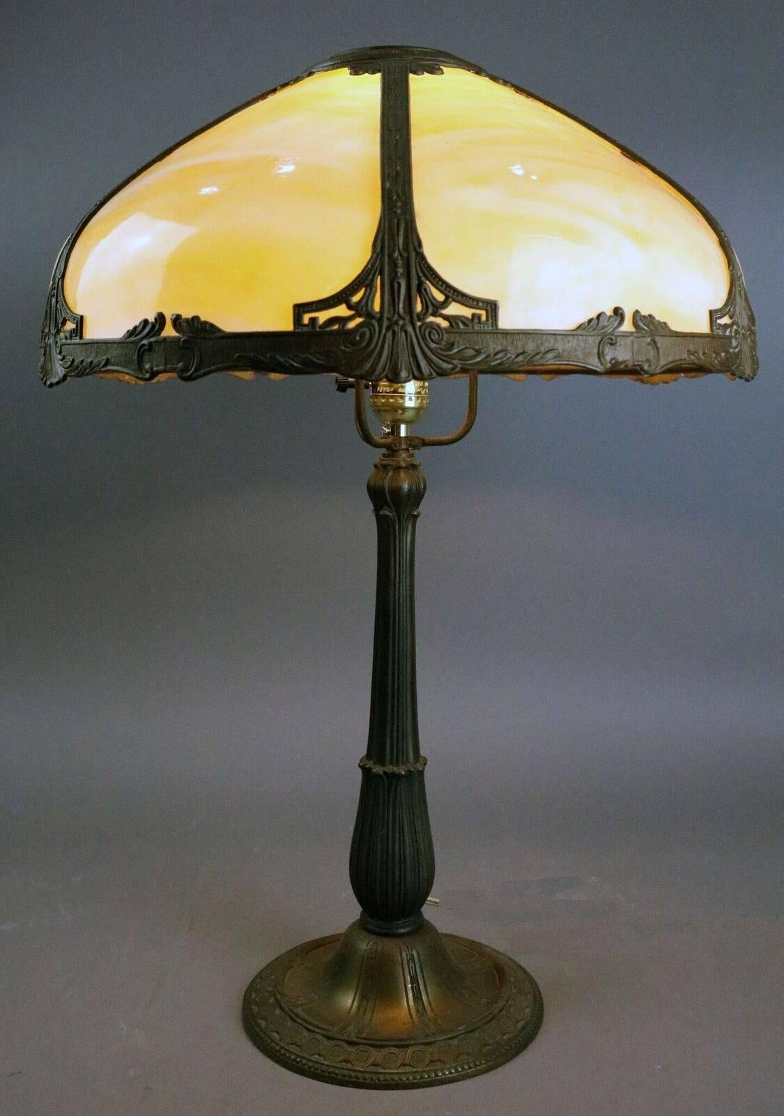 Antique Miller style Arts & Crafts lamp features cream curved glass panel shade with bronze finish cast metal frame and base, circa 1920.