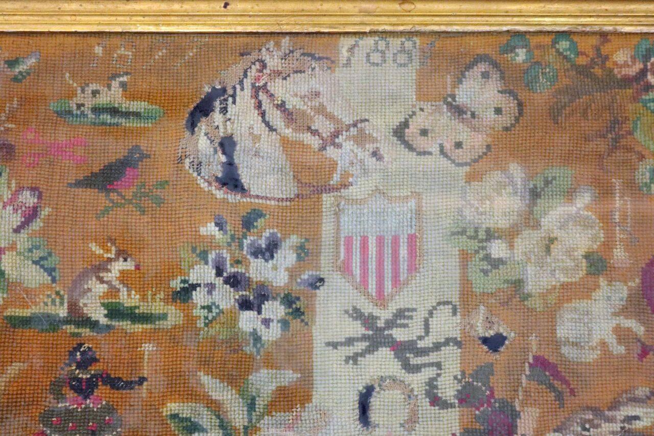 Antique framed Folk Art needlepoint sampler with Americana patriotic theme including shield of American Flag, black Americans, animals and birds, and monogram "M" and dated 1881.

Measures - 25.5"H x 20.75"W x 1.5"D