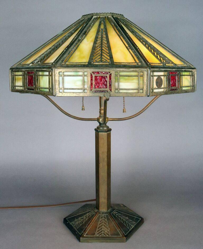 Antique Prairie School Frank Lloyd Wright Arts & Crafts Bradley & Hubbard brass table lamp features stylized feather motif, faceted shade lined with lime green and ruby red slag glass, stamped Bradley & Hubbard Mfg Co., re-wired, circa 1910.